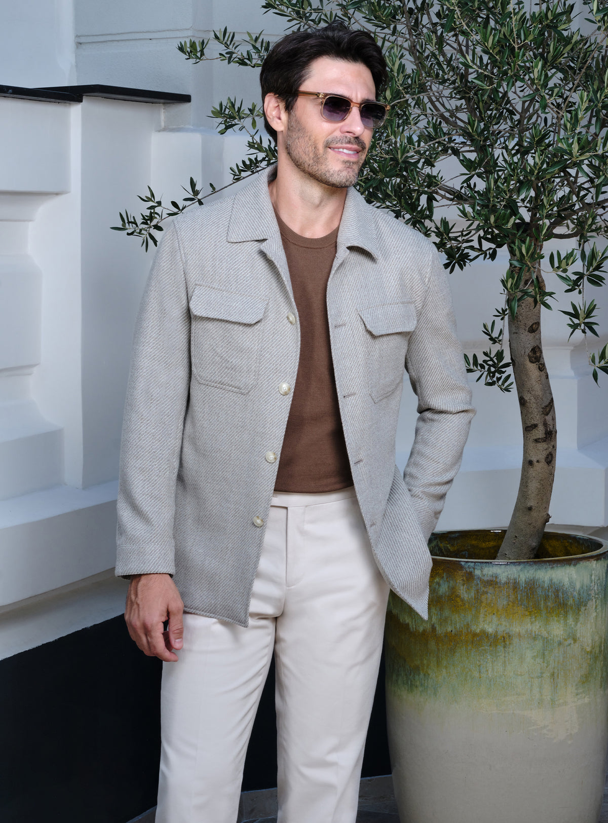 Light beige Consiglieri jacket with flap pockets, a brown sweater and white trousers