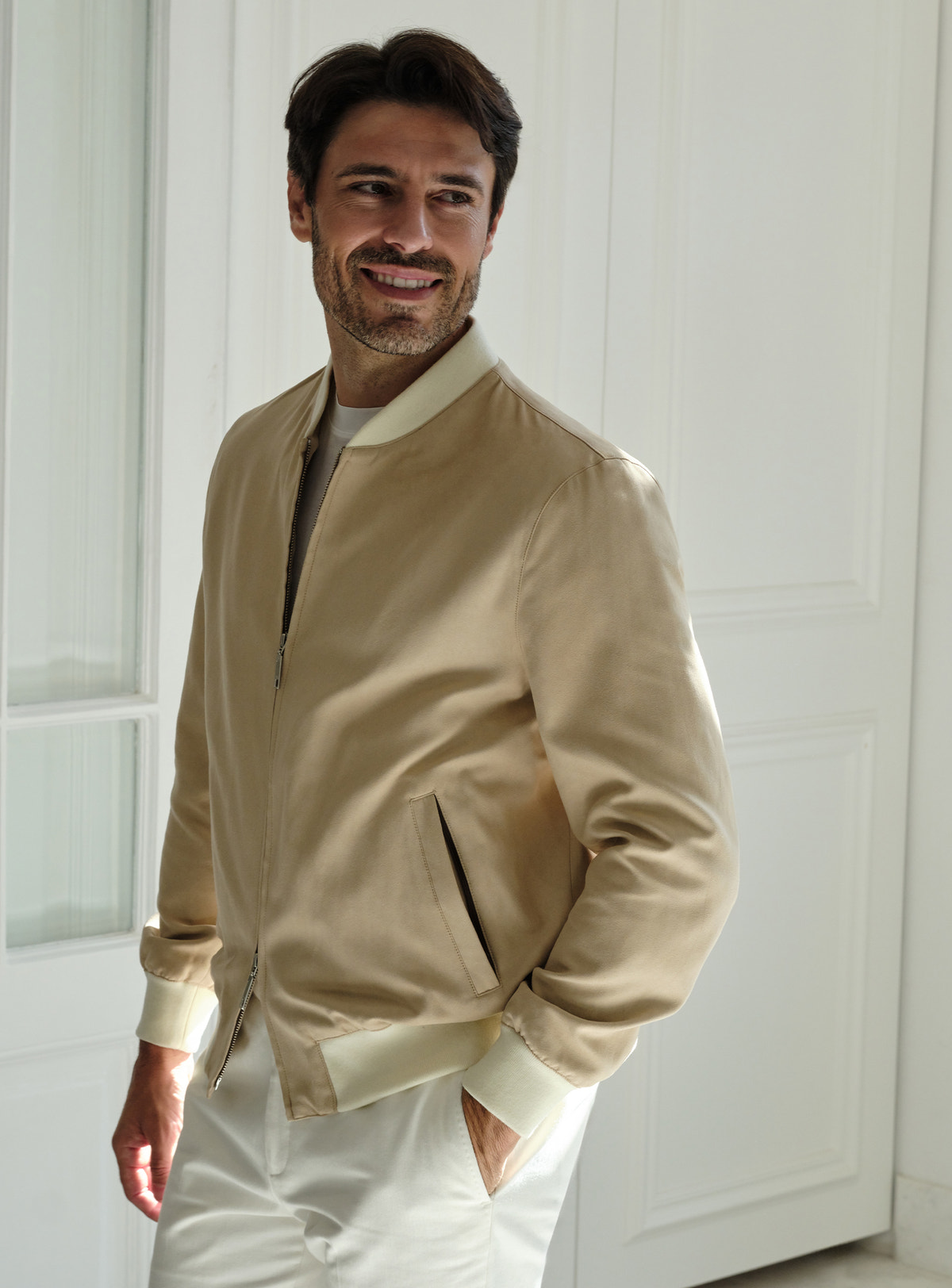 Beige Consiglieri zip bomber jacket worn with white trousers