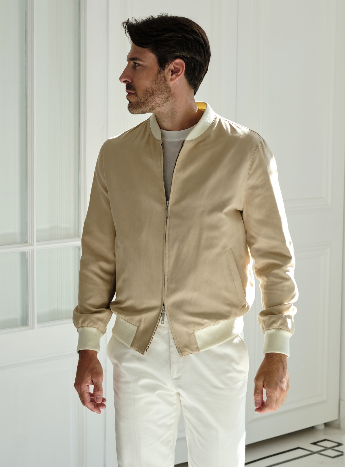 Beige Consiglieri zip bomber jacket worn with white trousers