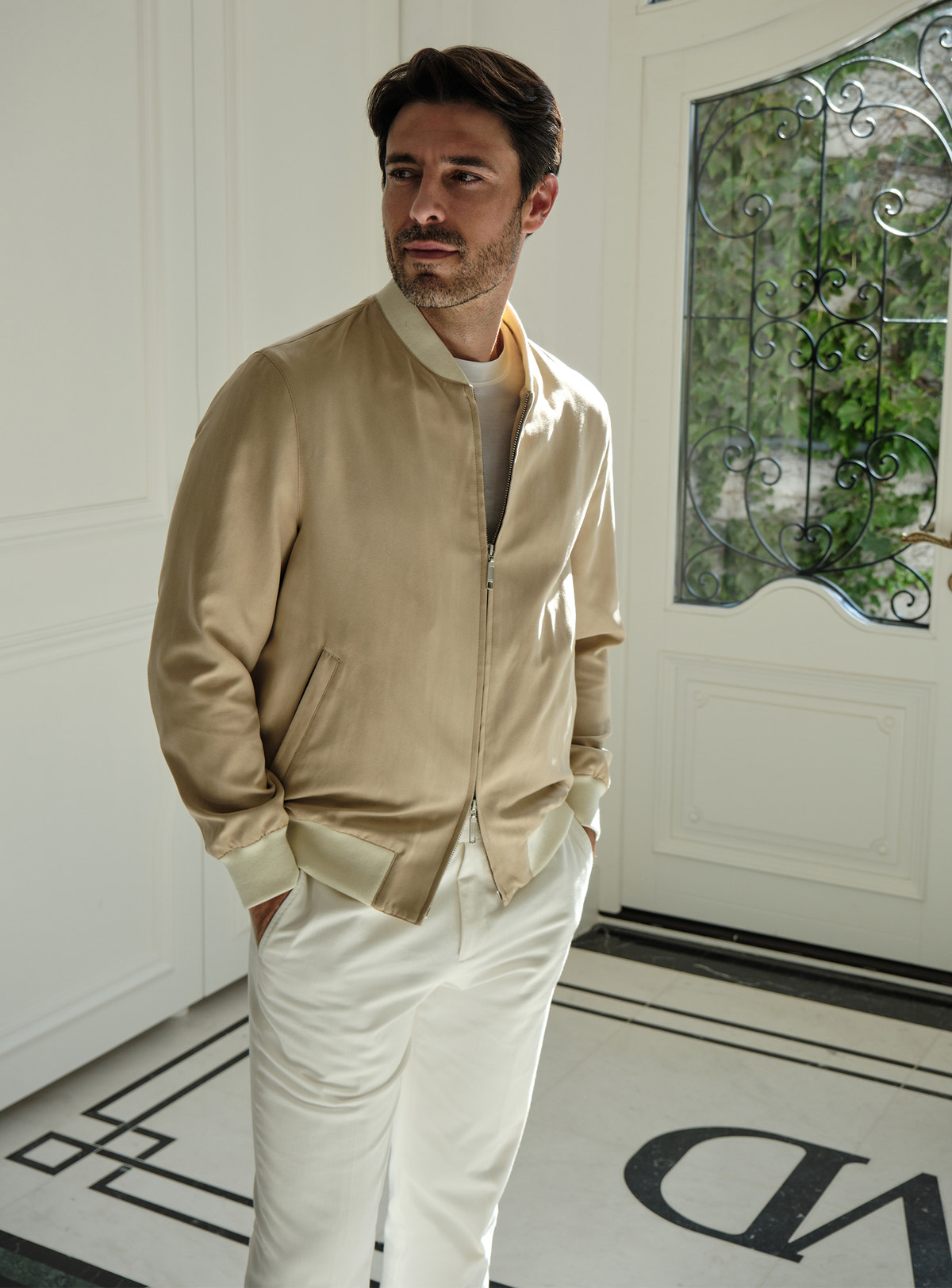 Beige Consiglieri zip bomber jacket worn with white trousers