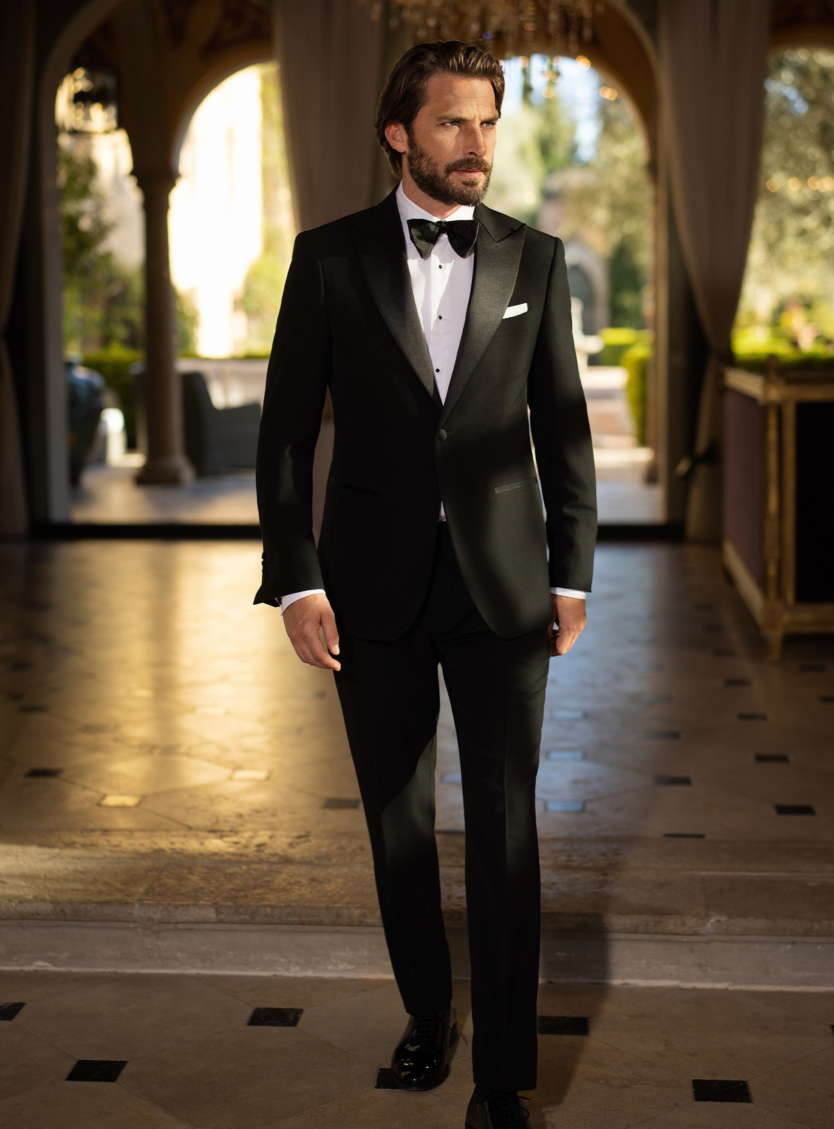 Black Consiglieri tuxedo with lustrous lapels, a white shirt and black bow tie