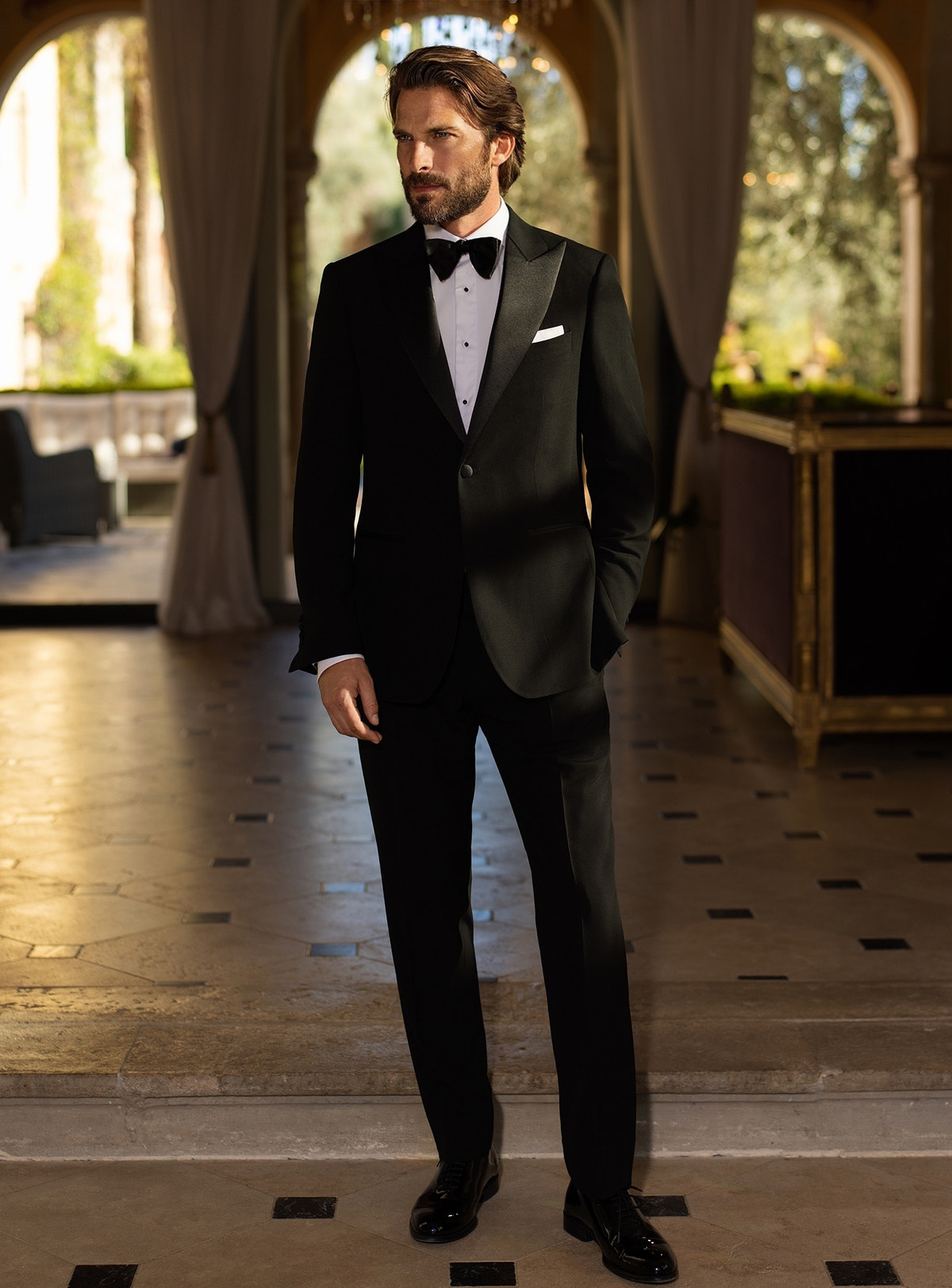 Black Consiglieri tuxedo with lustrous lapels, a white shirt and black bow tie