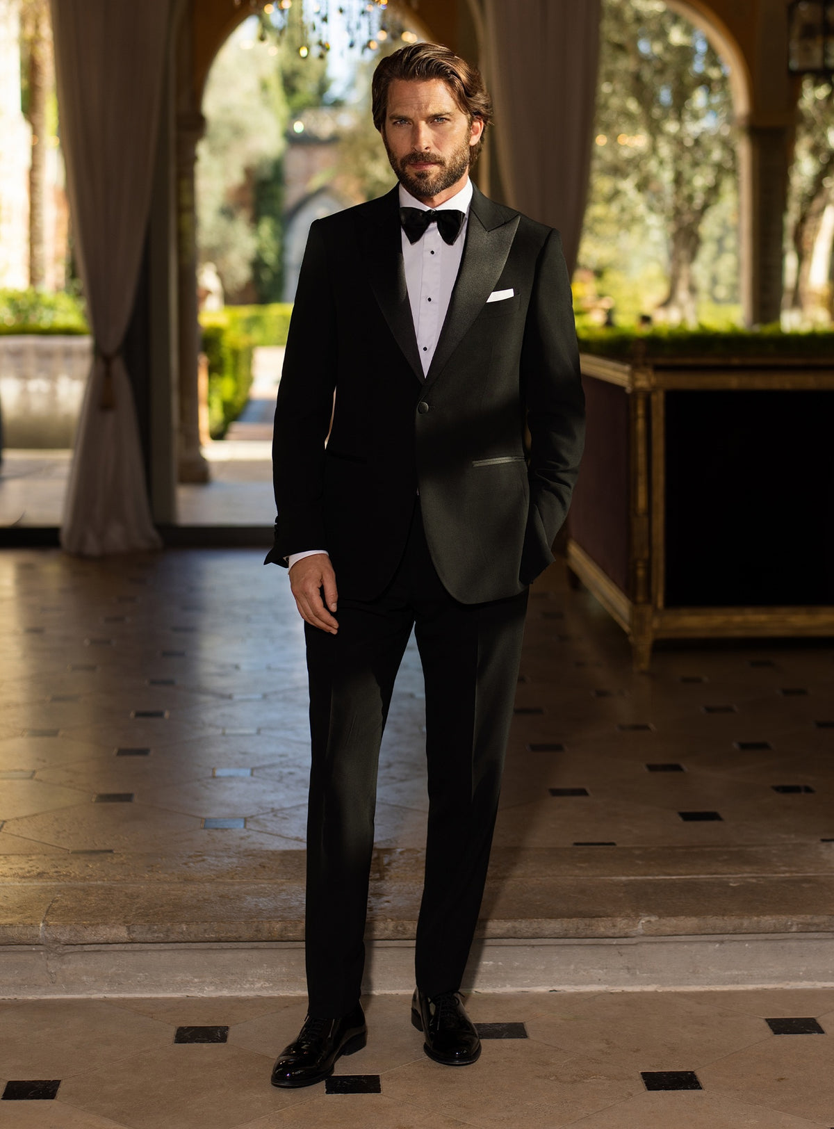 Black Consiglieri tuxedo with lustrous lapels, a white shirt and black bow tie
