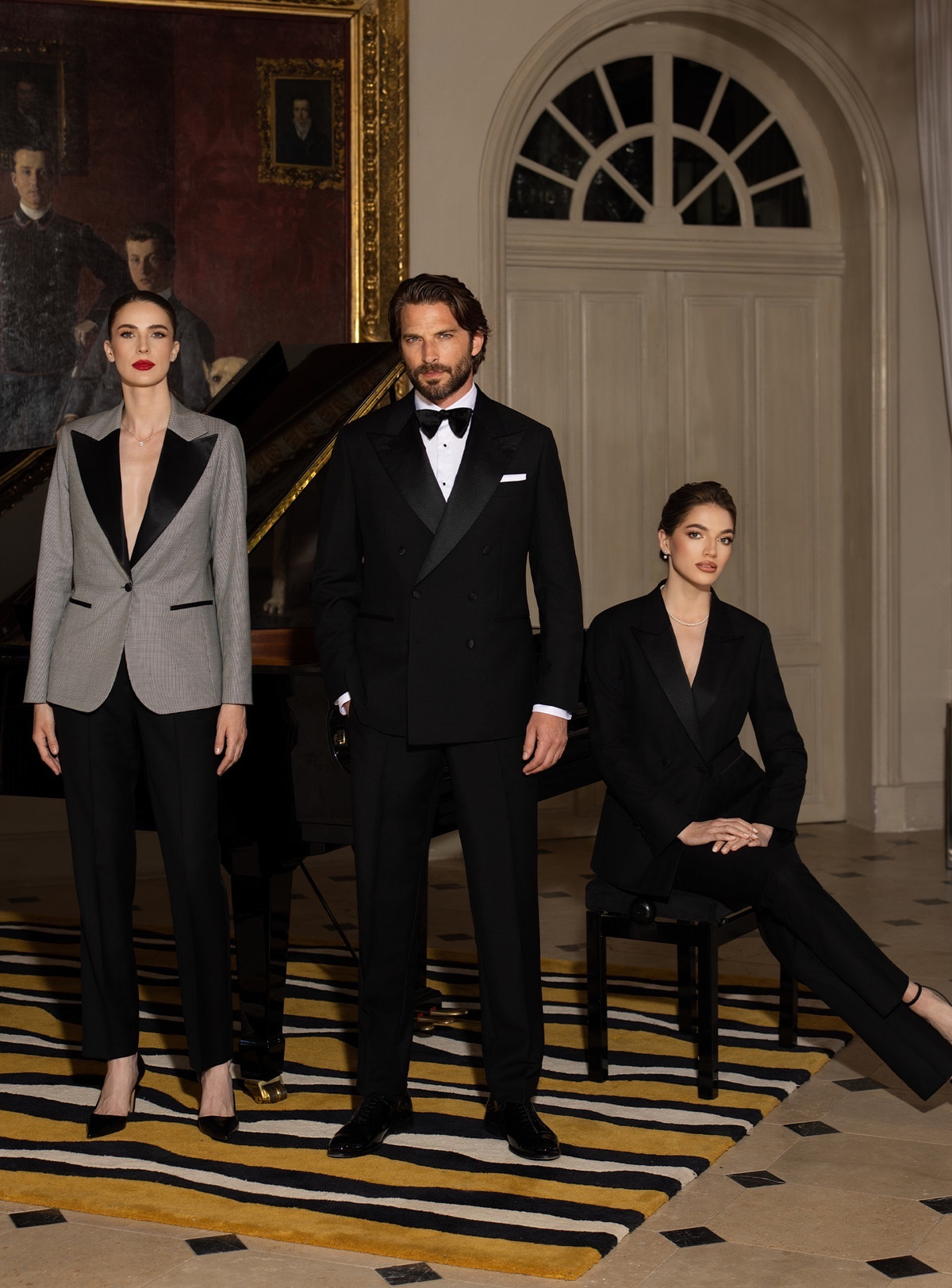 Consiglieri women's and men's tuxedos in black and grey beside a piano