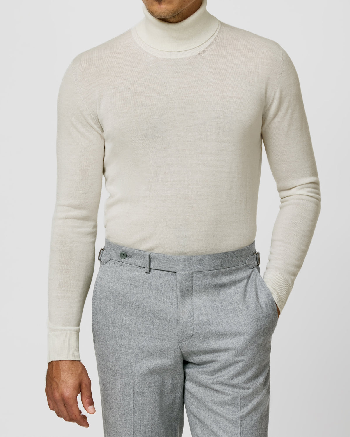 Cream Consiglieri turtleneck worn with grey trousers