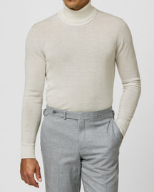 Cream Consiglieri turtleneck worn with grey trousers