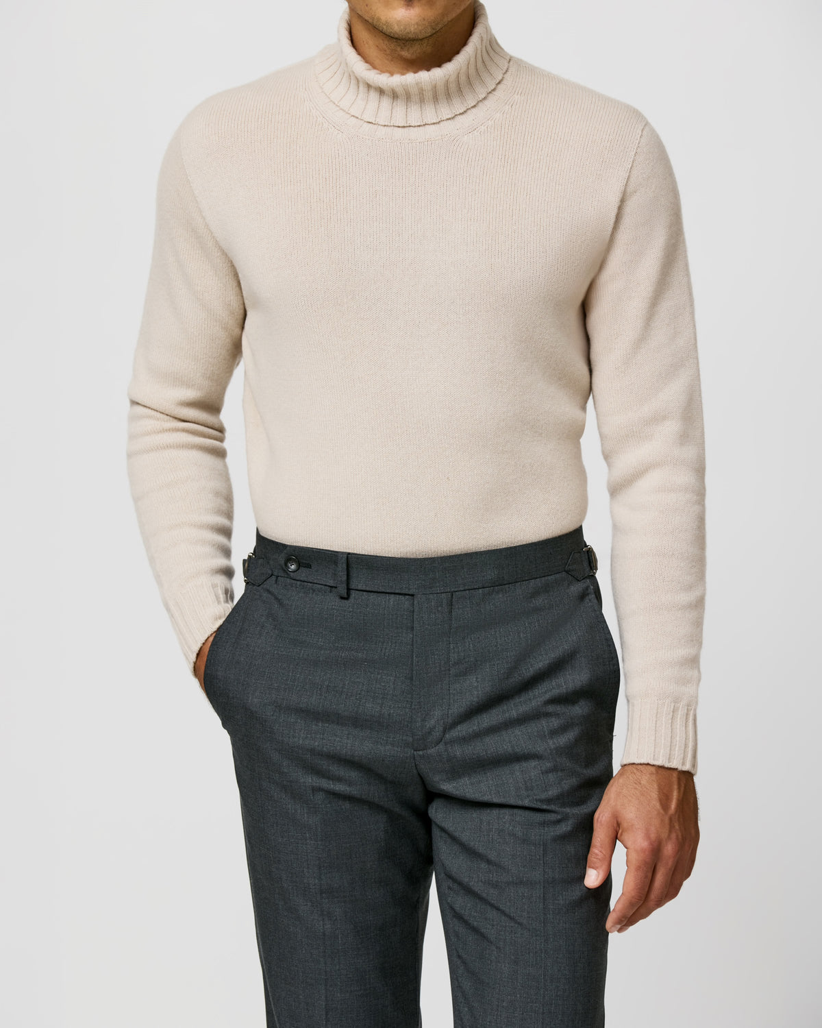 Light beige Consiglieri turtleneck with a ribbed collar, worn with dark trousers