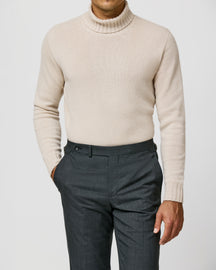 Light beige Consiglieri turtleneck with a ribbed collar, worn with dark trousers