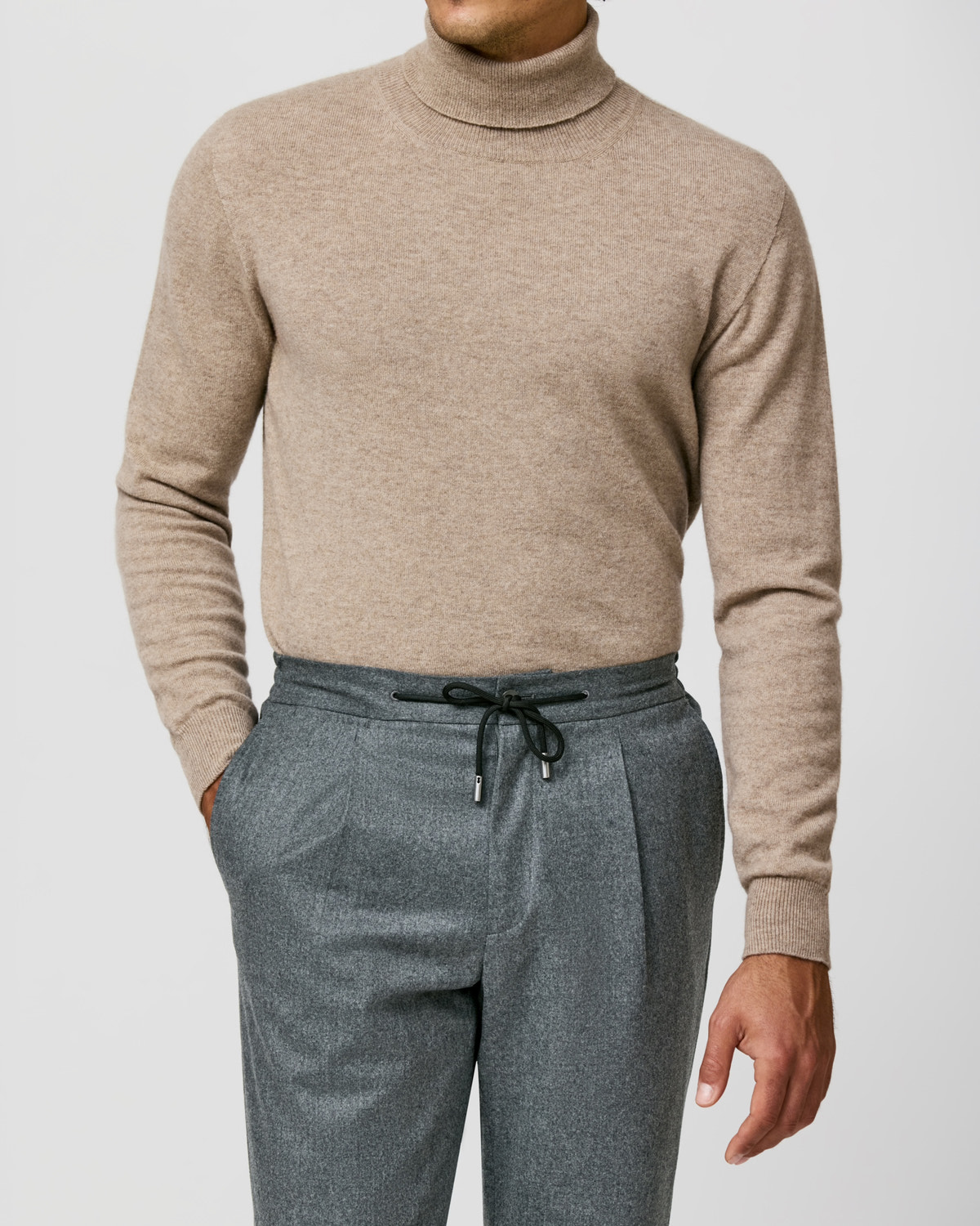 Beige Consiglieri turtleneck worn with grey drawstring trousers