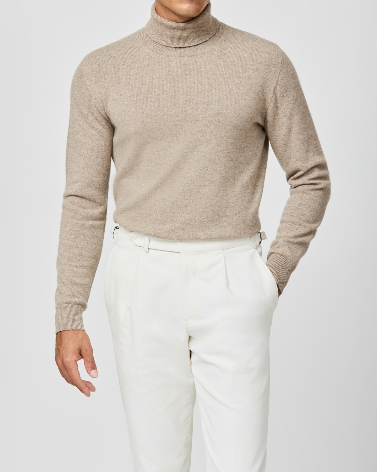 Beige Consiglieri turtleneck worn with pleated white trousers