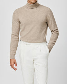 Beige Consiglieri turtleneck worn with pleated white trousers