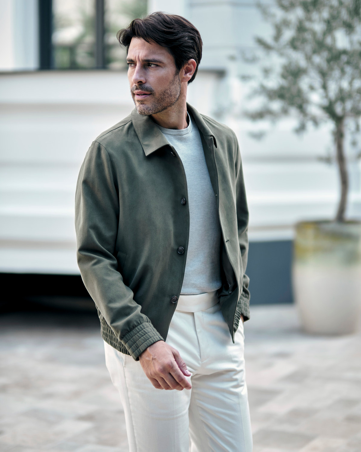 Olive green Consiglieri jacket with a shirt collar, a grey sweater and white trousers