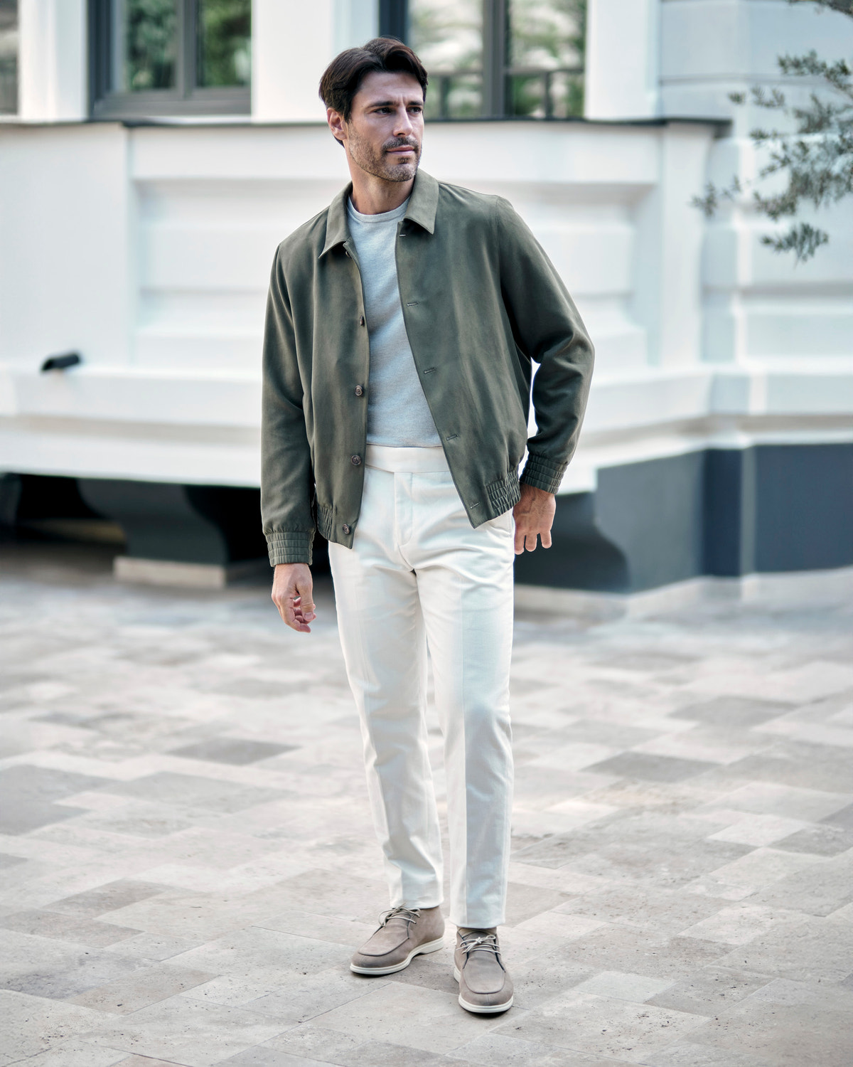 Olive green Consiglieri jacket with a shirt collar, a grey sweater and white trousers