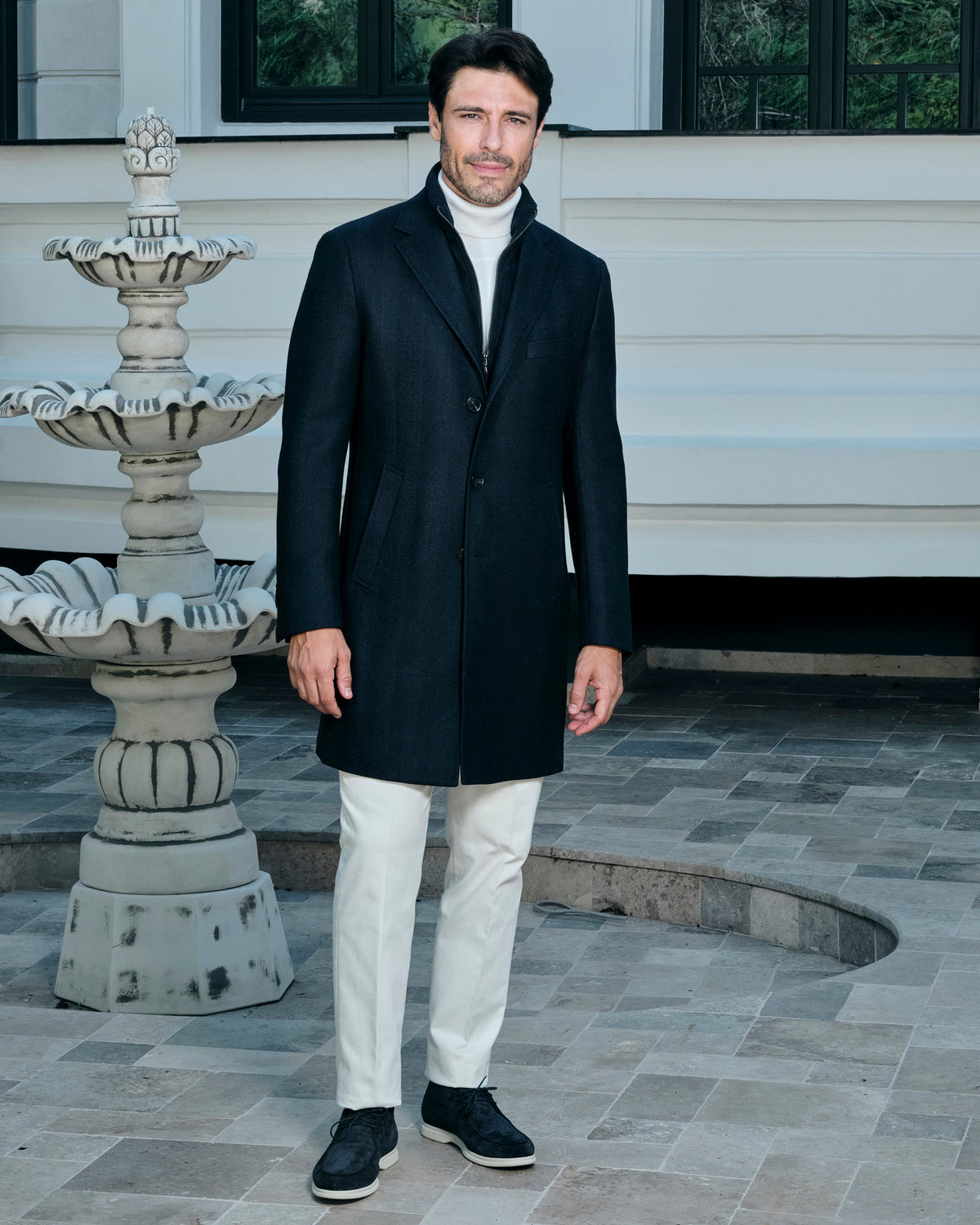 Black Consiglieri coat with a shirt collar, worn with white trousers
