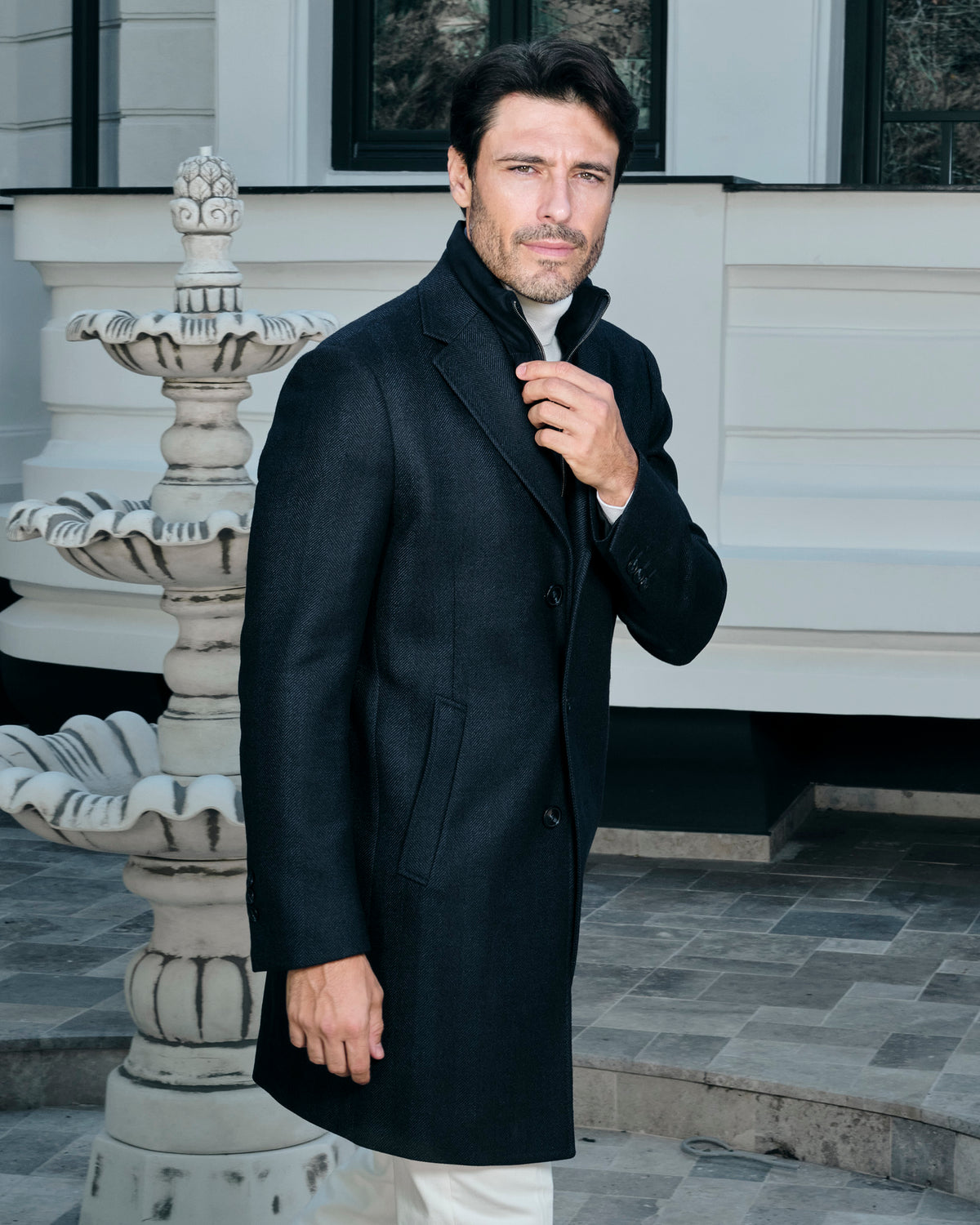 Black Consiglieri coat with a shirt collar, worn with white trousers