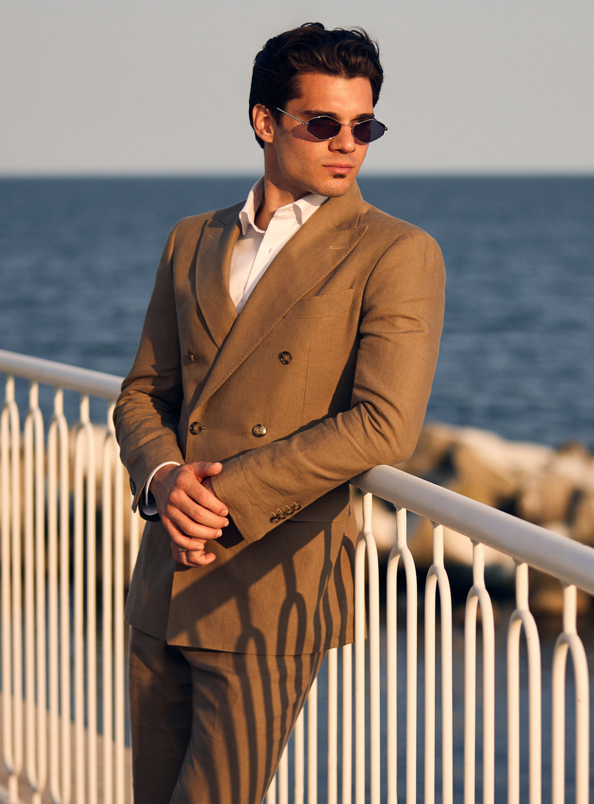 Brown double-breasted Consiglieri suit worn with an open-neck white shirt