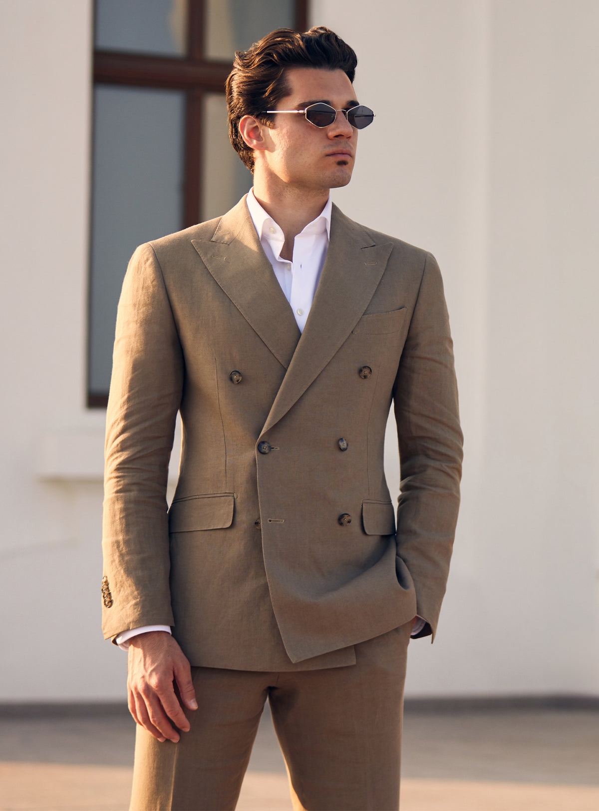 Brown double-breasted Consiglieri suit worn with an open-neck white shirt