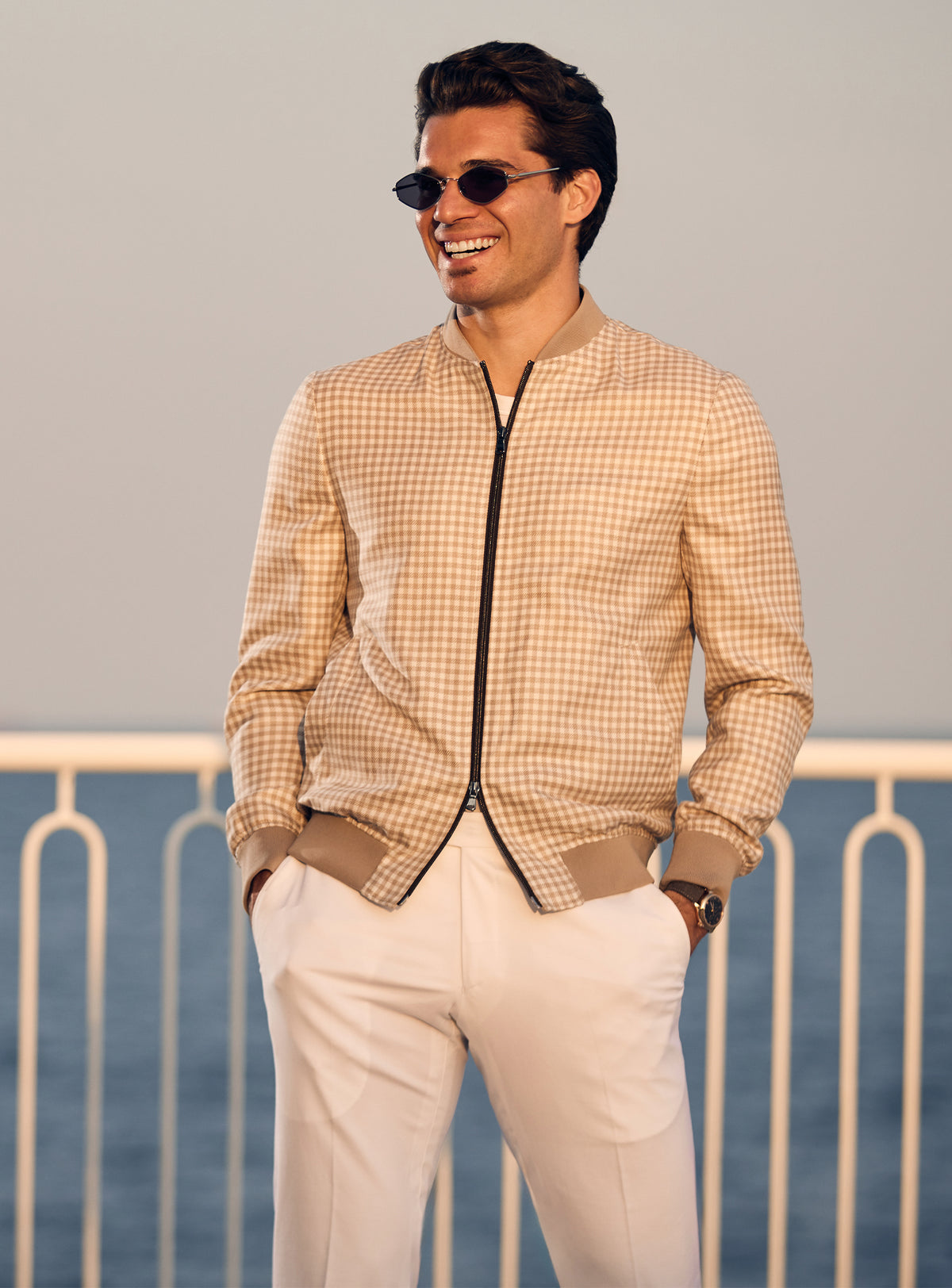 Beige Consiglieri bomber jacket with a subtle pattern and dark zip, worn with white trousers