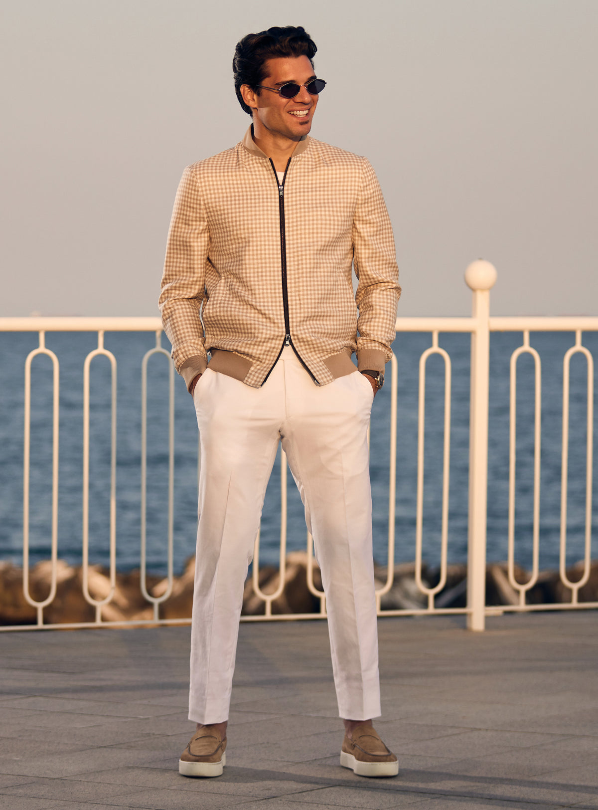 Beige Consiglieri bomber jacket with a subtle pattern and dark zip, worn with white trousers
