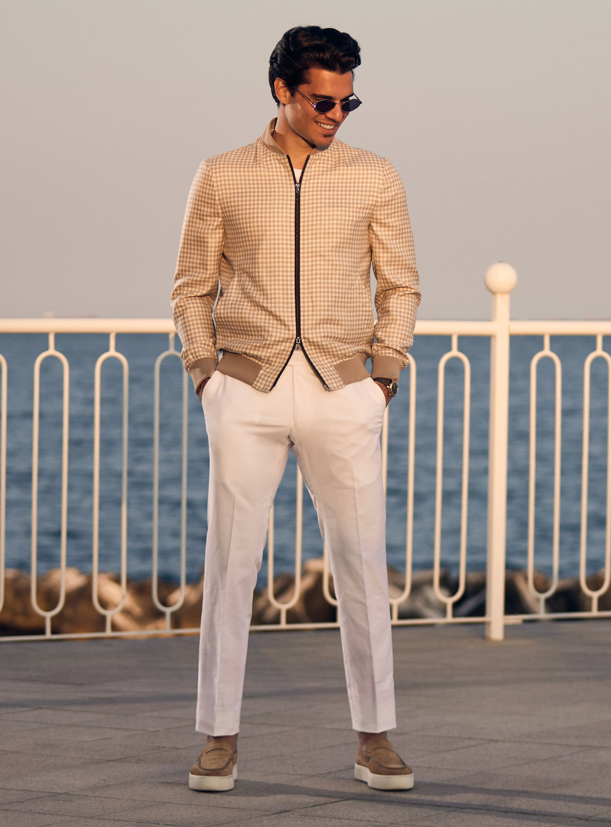 Beige Consiglieri bomber jacket with a subtle pattern and dark zip, worn with white trousers