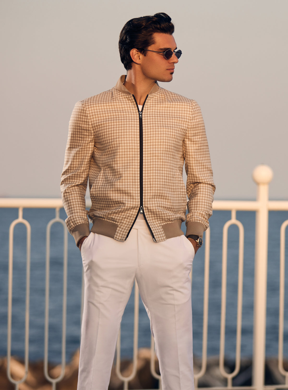 Beige Consiglieri bomber jacket with a subtle pattern and dark zip, worn with white trousers
