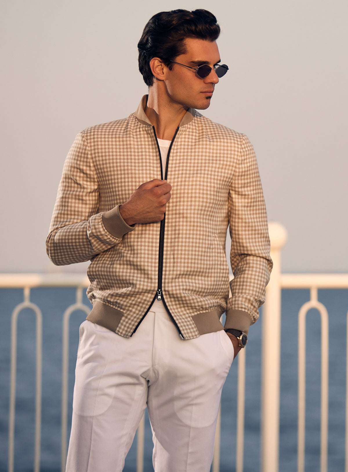 Beige Consiglieri bomber jacket with a subtle pattern and dark zip, worn with white trousers