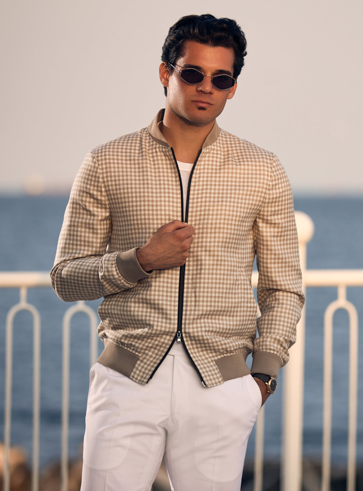 Beige Consiglieri bomber jacket with a subtle pattern and dark zip, worn with white trousers