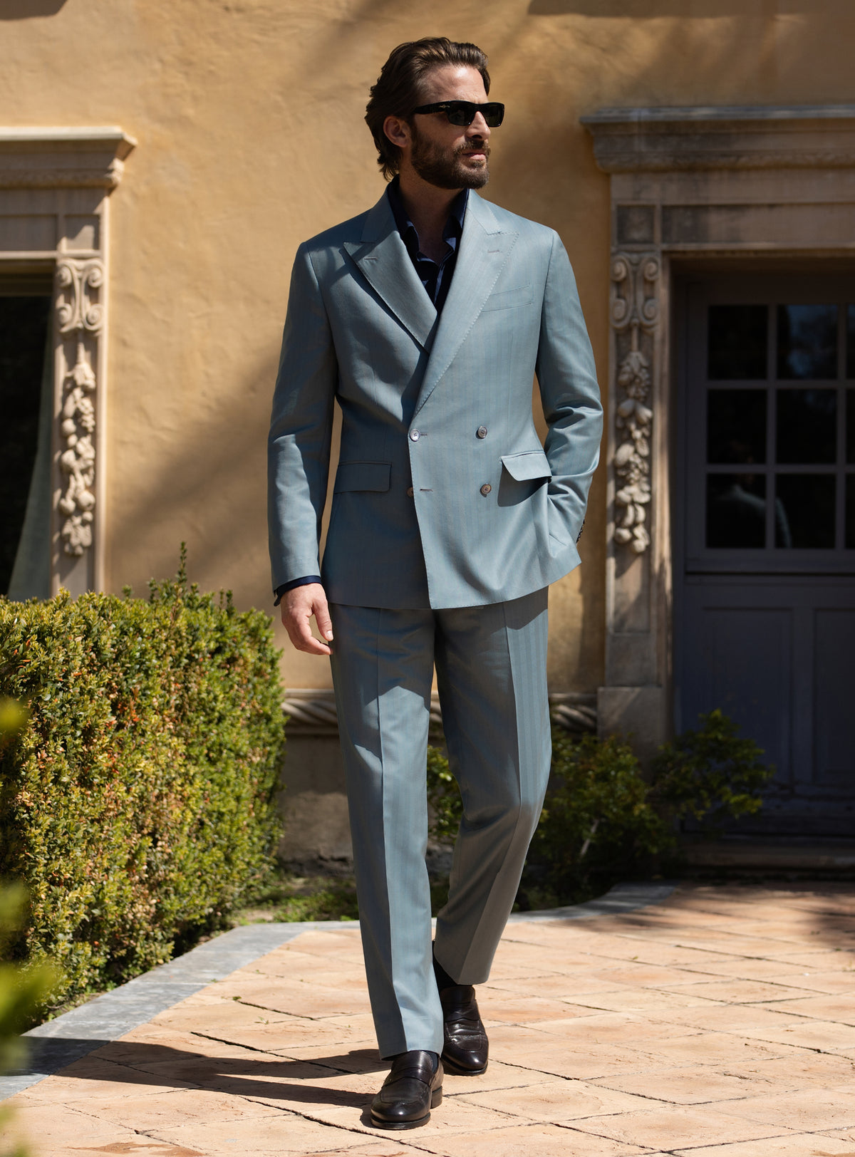 Blue-grey double-breasted Consiglieri suit worn with a dark shirt