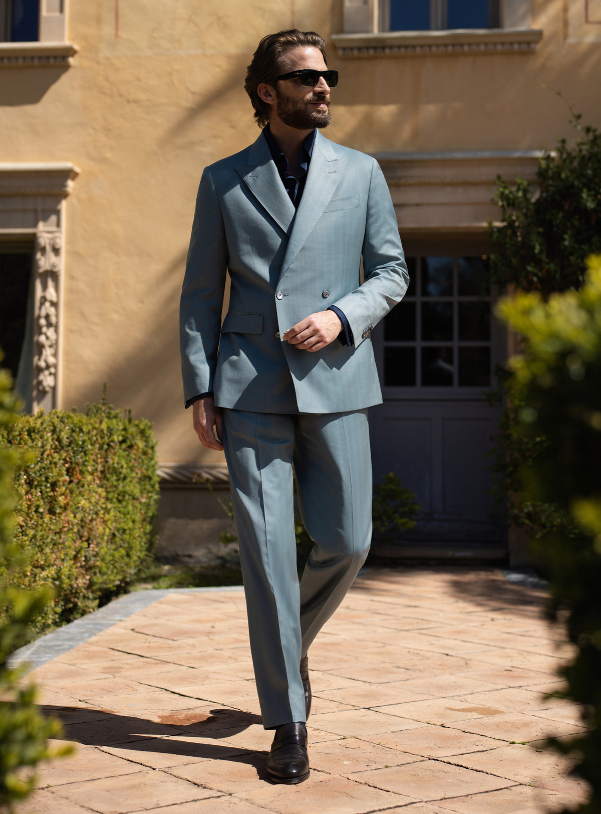 Blue-grey double-breasted Consiglieri suit worn with a dark shirt