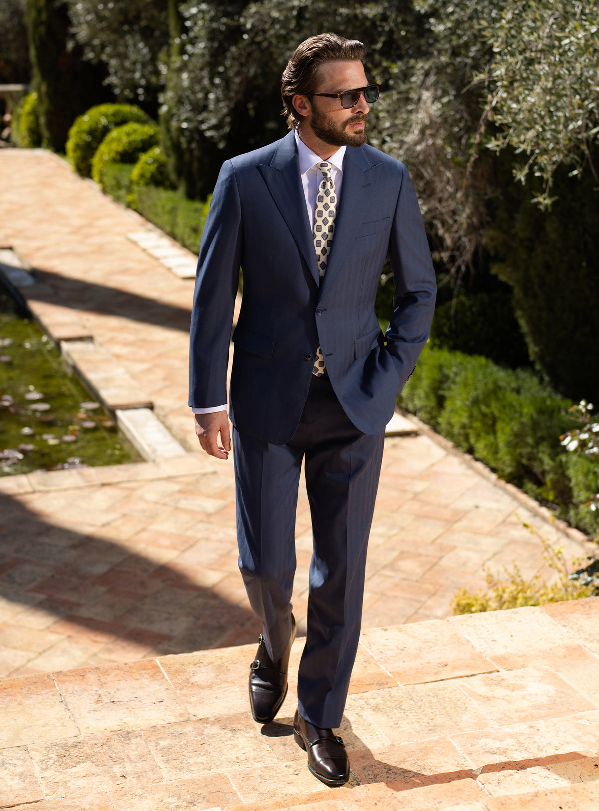 Navy Consiglieri suit with notch lapels, worn with a light patterned tie