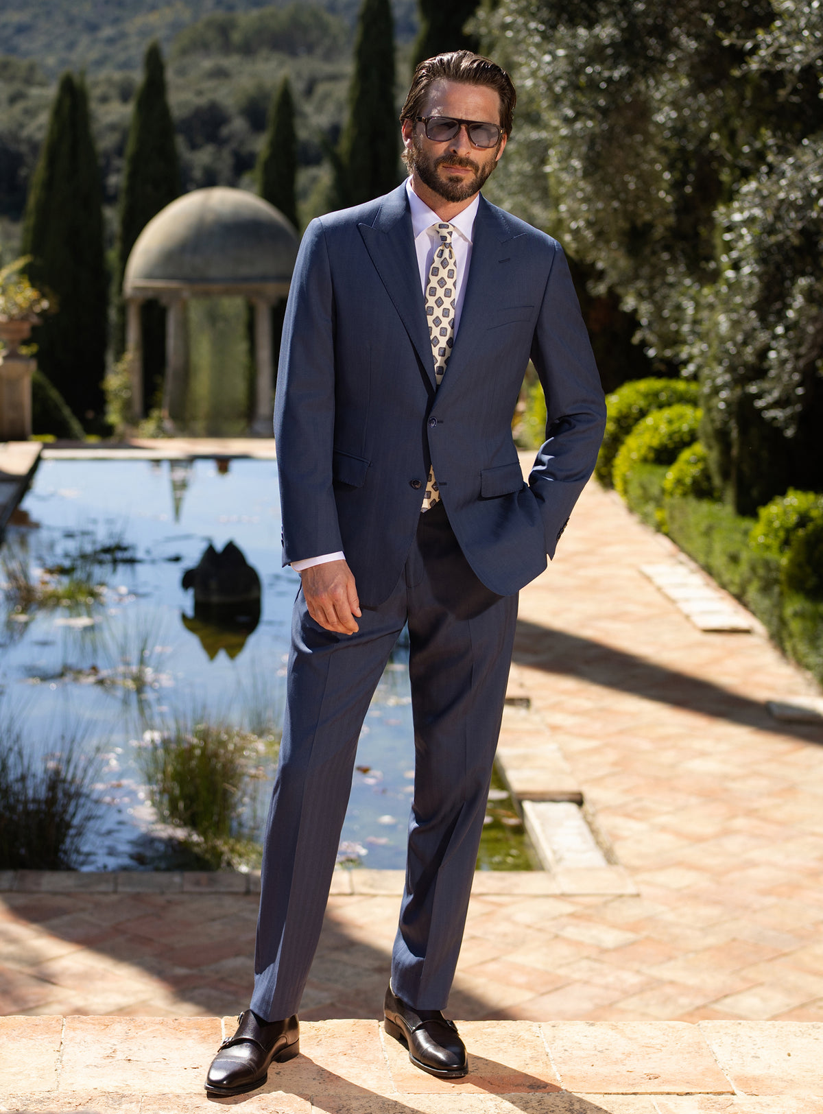 Navy Consiglieri suit with notch lapels, worn with a light patterned tie