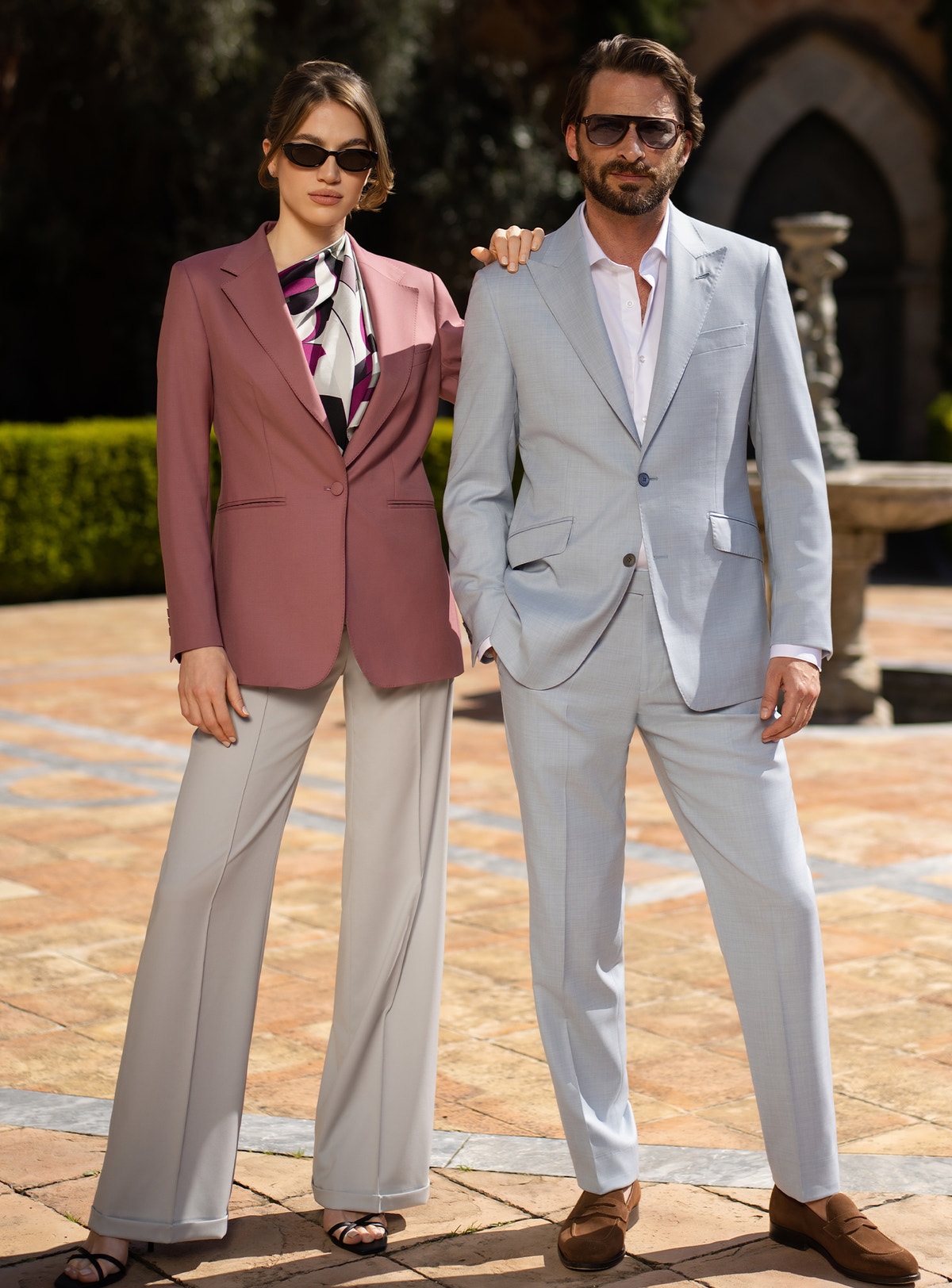 Pale blue men's suit and women's look with a pink blazer and cream trousers by Consiglieri