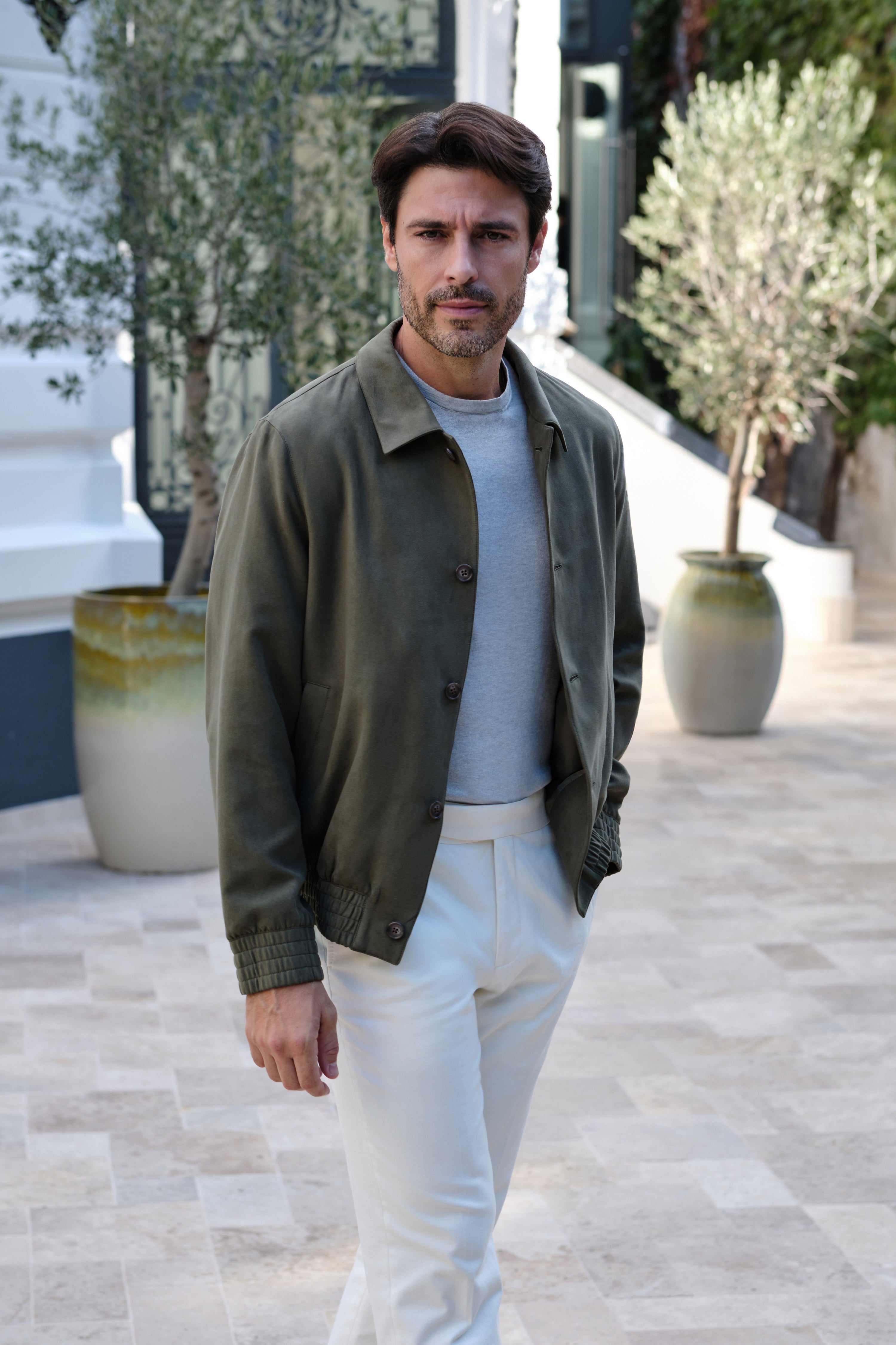 Olive blouson with a well-defined collar and button closure, photographed outdoors