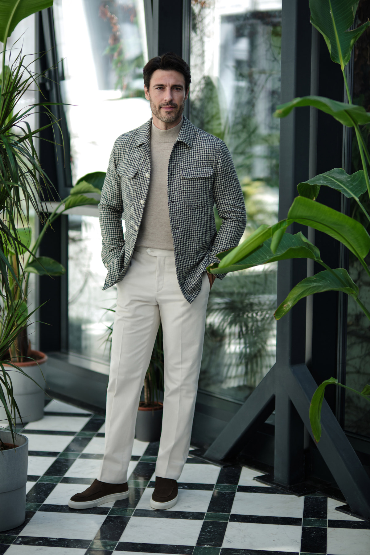 Grey jacket with light trousers in a plant-filled interior