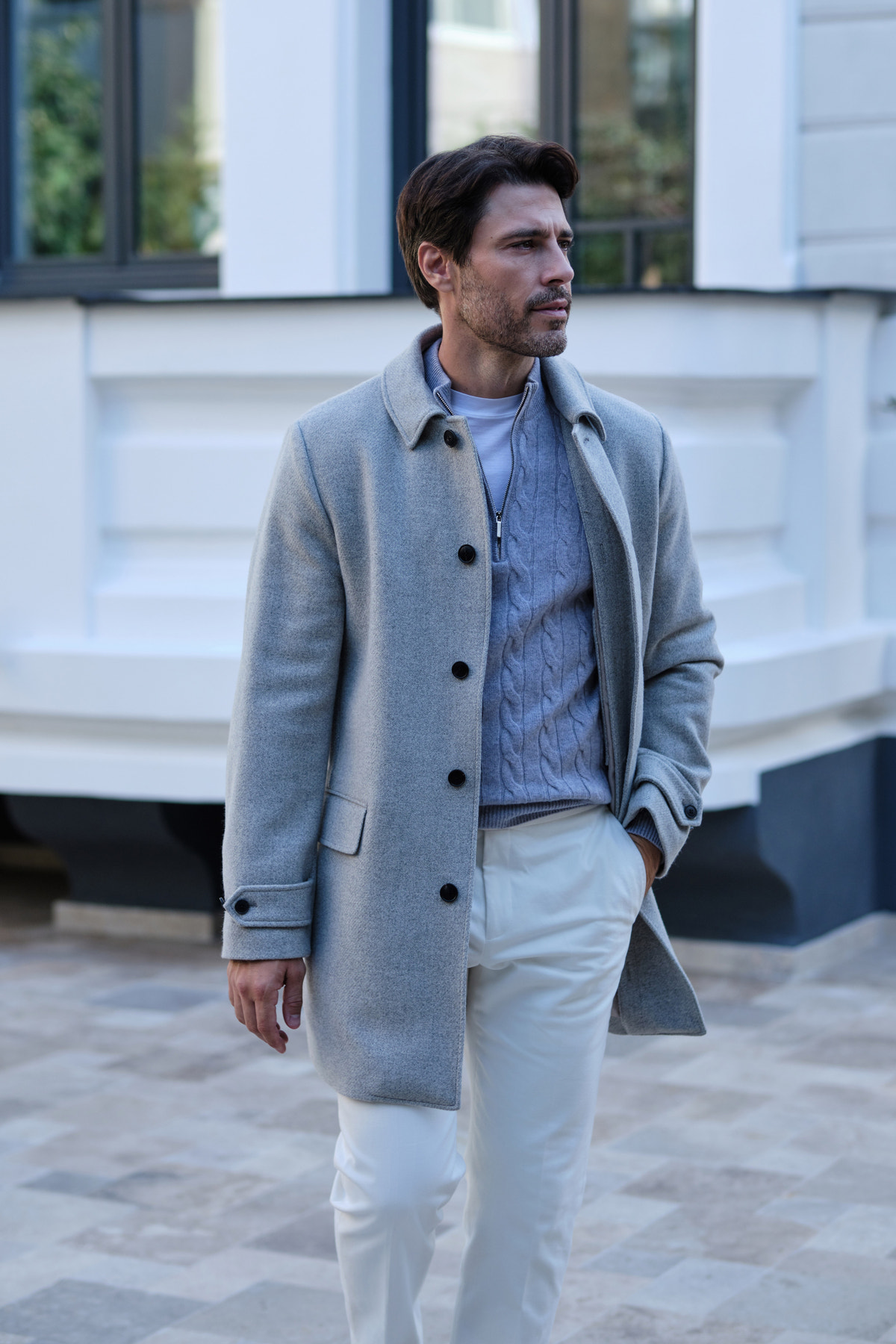 Light grey coat over a blue jumper and ivory trousers