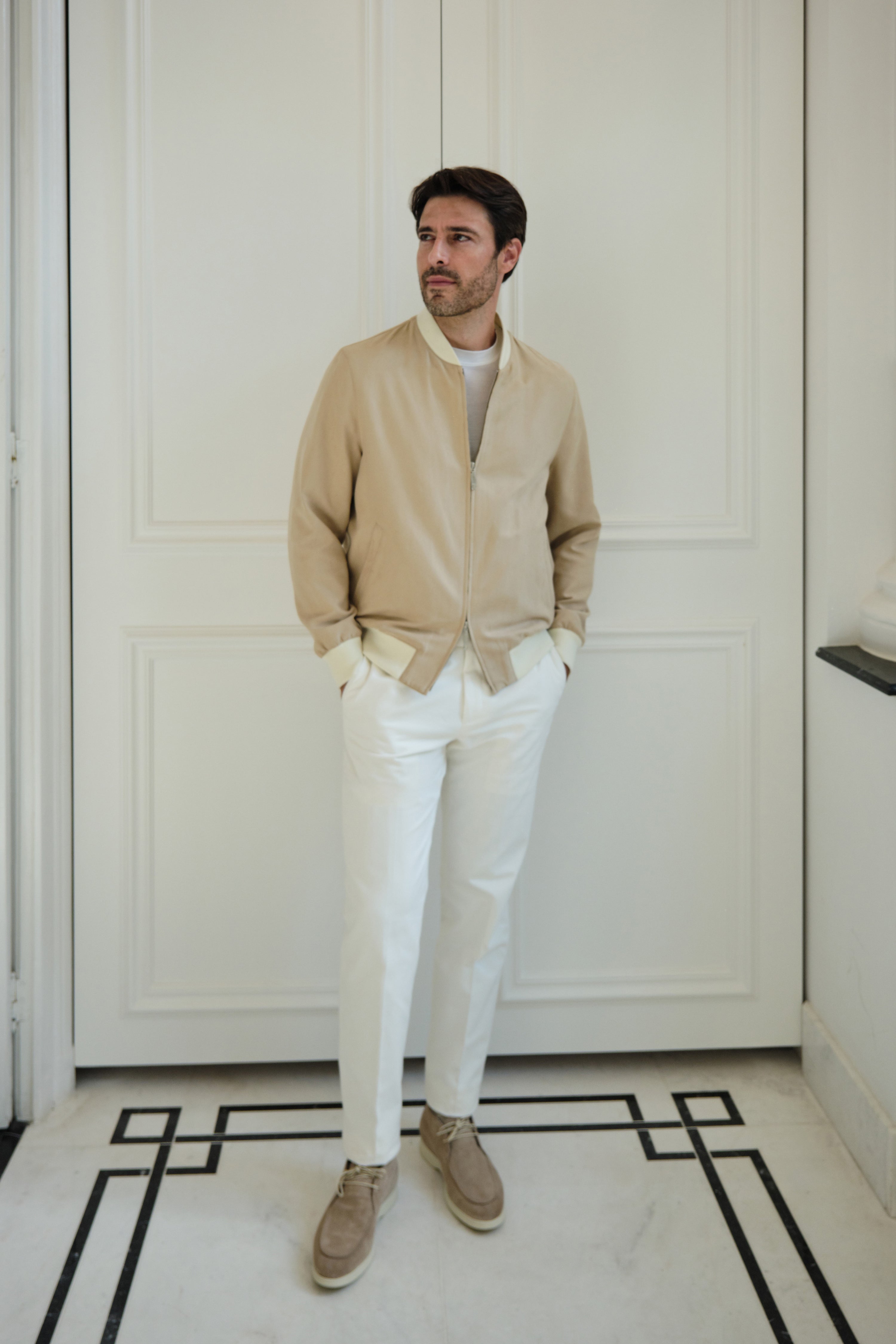 Complete outfit with a sand Bomber jacket, photographed in front of an entrance