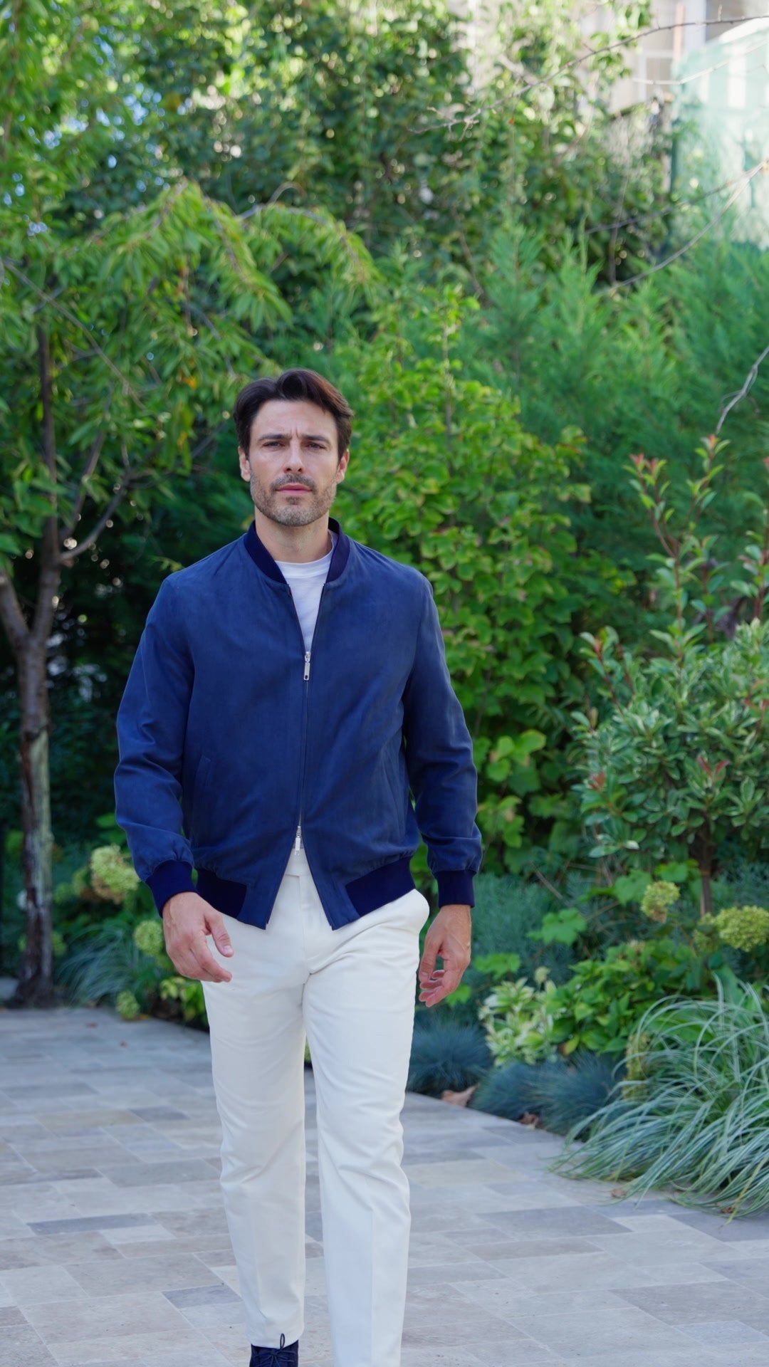 Navy Bomber jacket in motion, in a garden setting