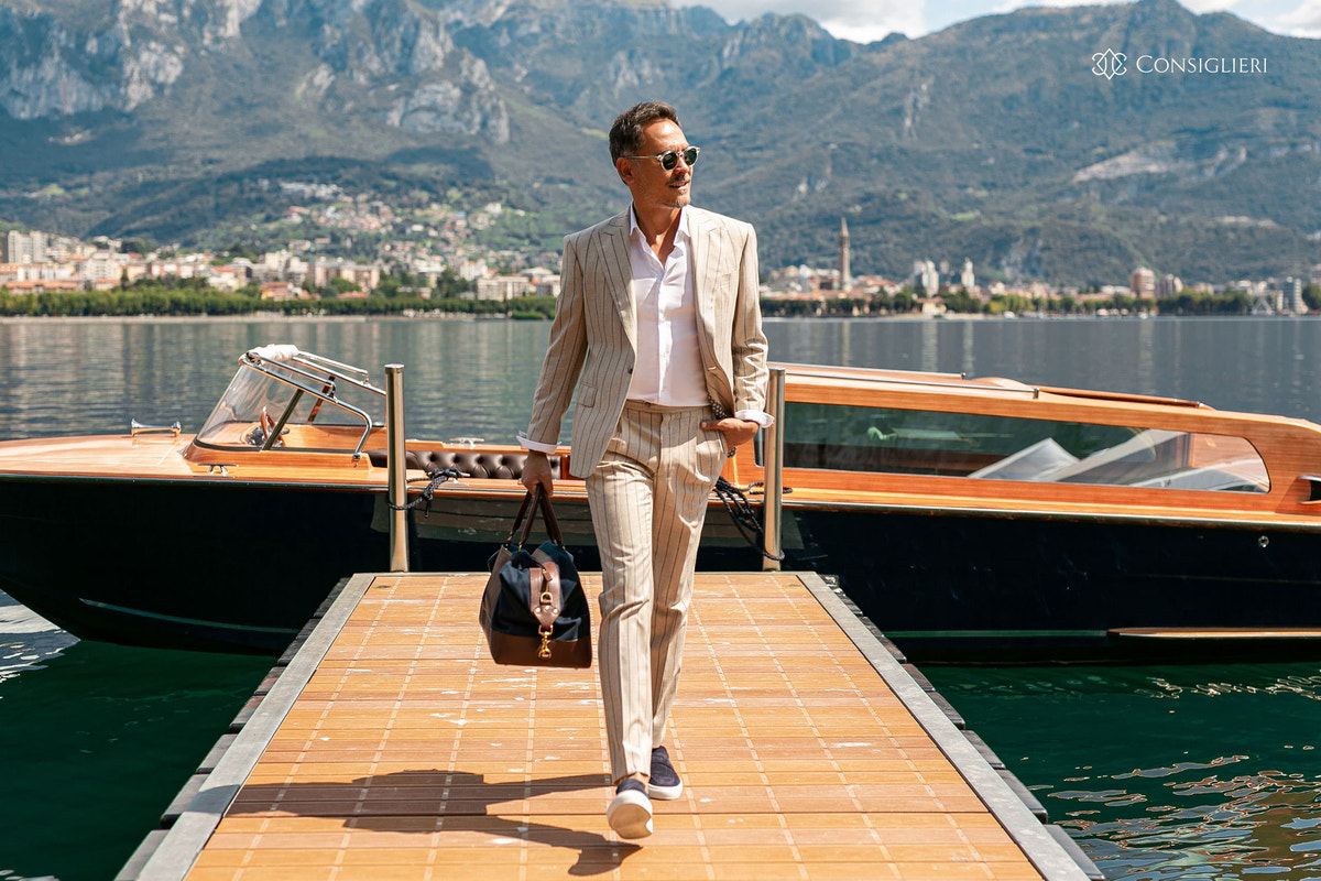 Beige Consiglieri suit styled with a bag on a jetty