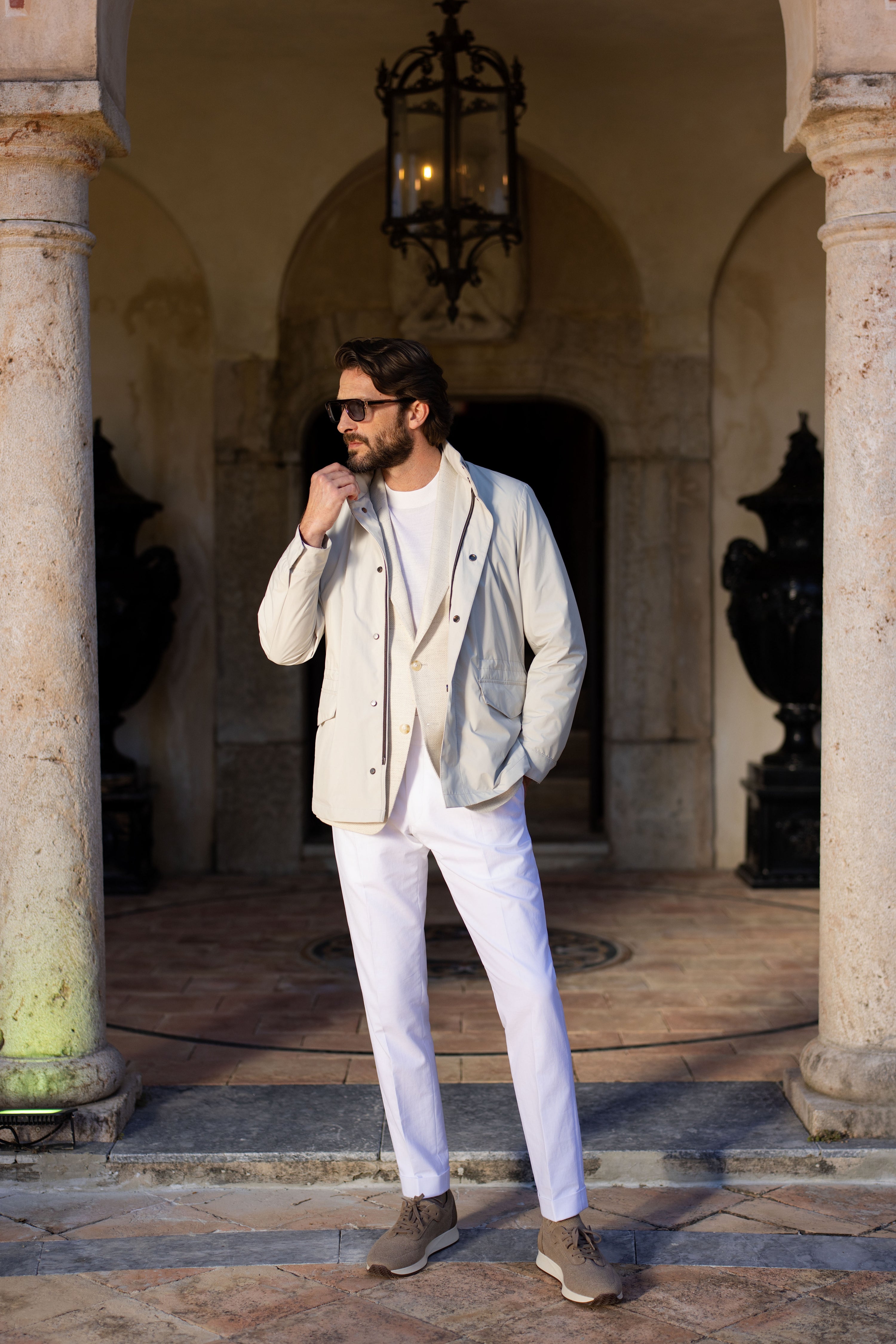 Light-coloured blouson worn in a complete look, in an architectural setting