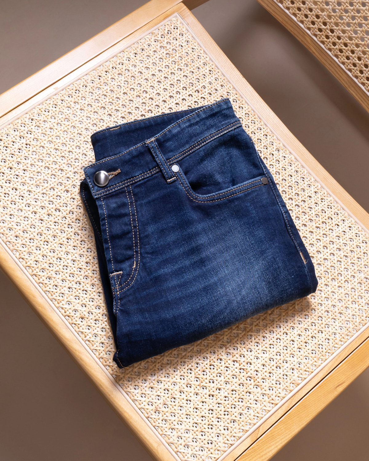 Navy denim with a metal button and tobacco stitching.