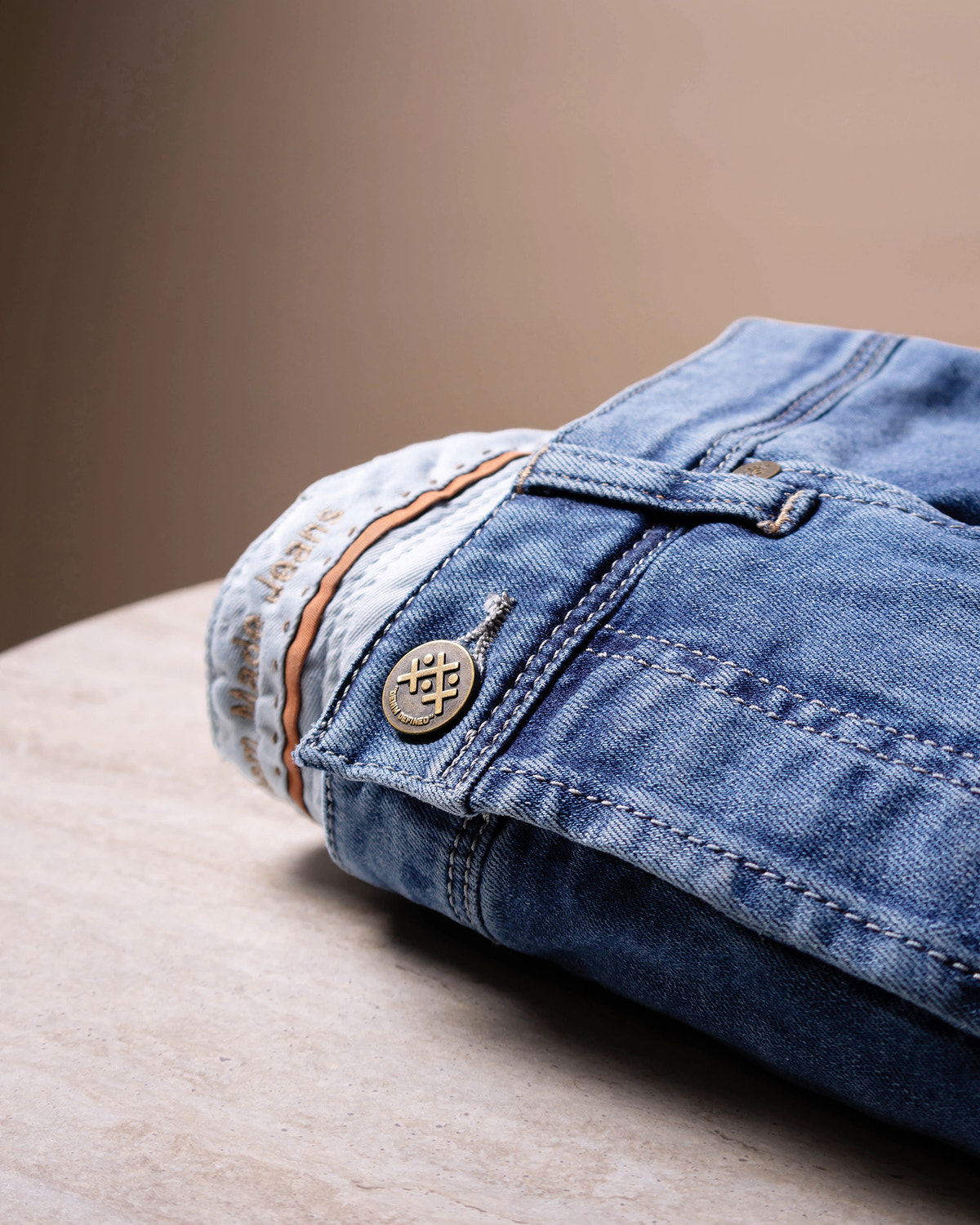 Washed blue denim with a metal button and silver-coloured stitching.