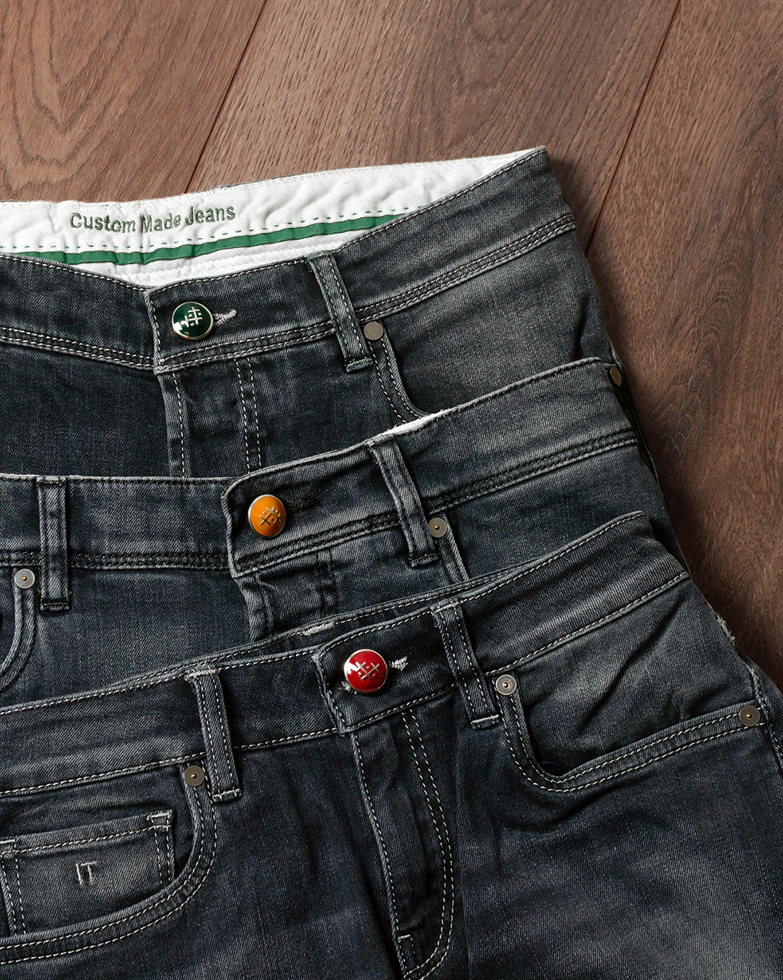 Three charcoal denim examples with coloured buttons — detail options.