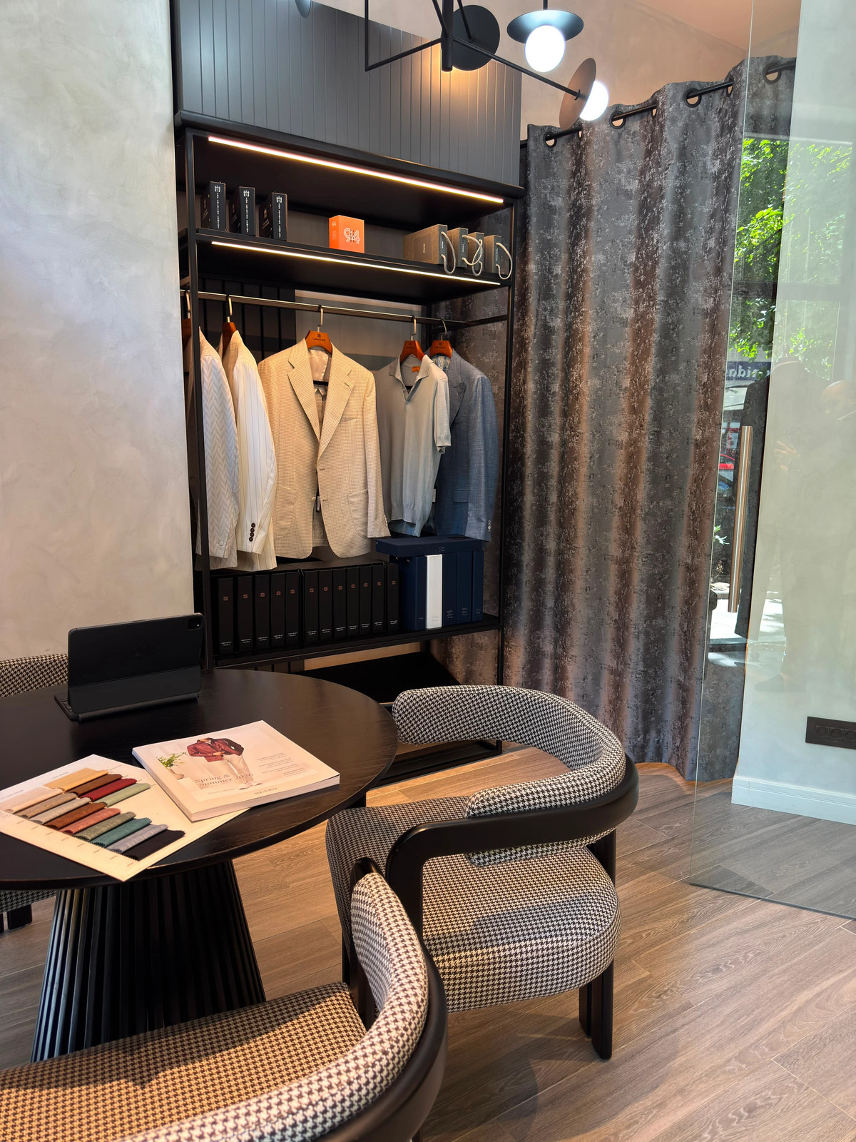 Fabric swatches on the consultation table, with jackets and shirts displayed behind it.