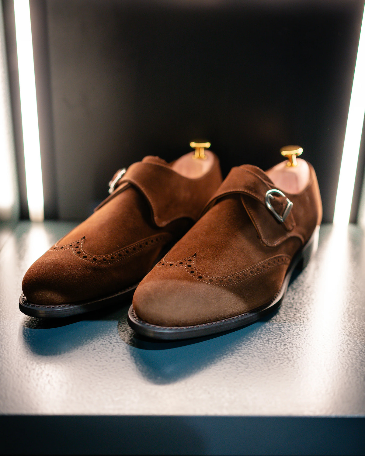 Brown buckle shoes with decorative broguing, shown in detail.