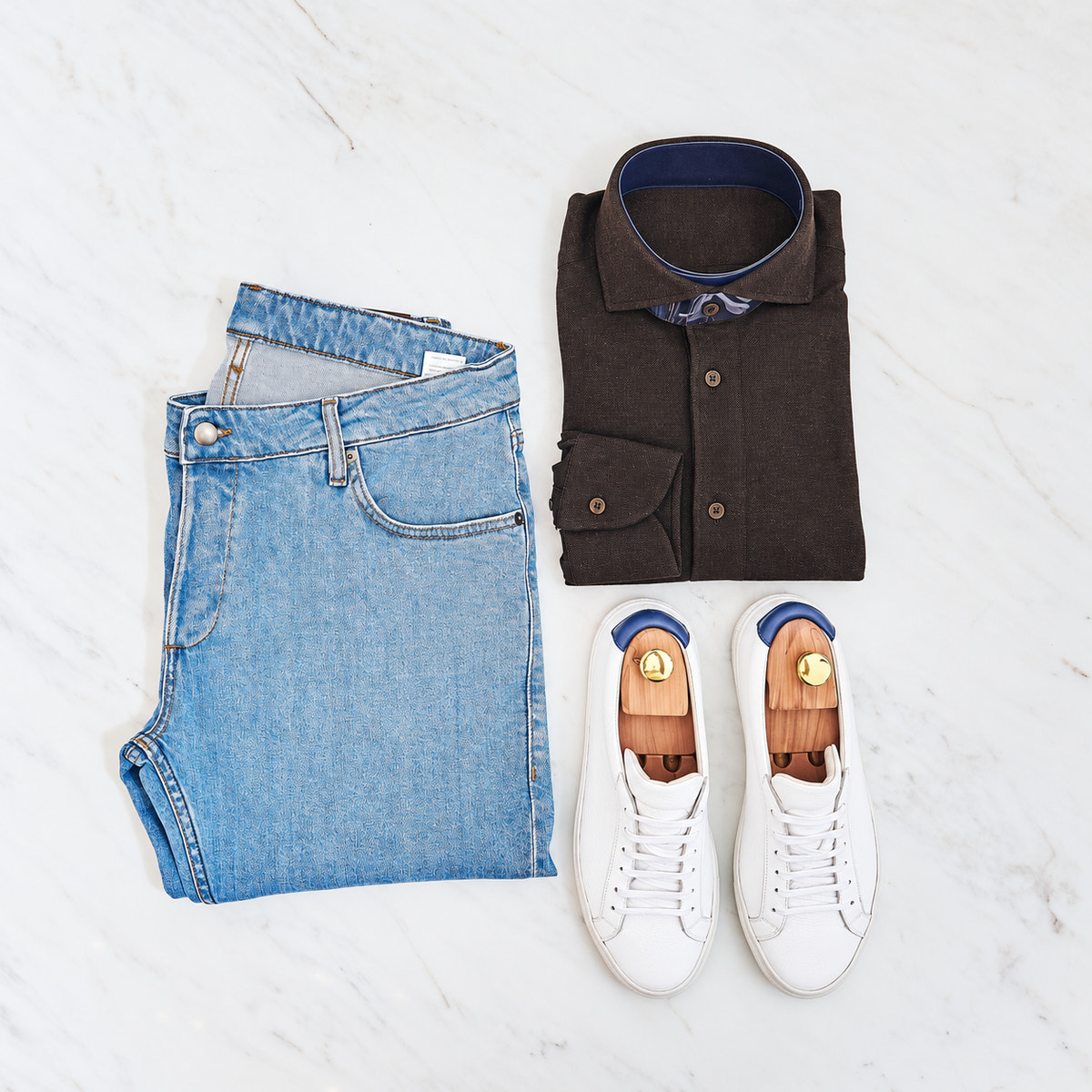 Blue jeans, a dark shirt and white Consiglieri sneakers arranged as an outfit