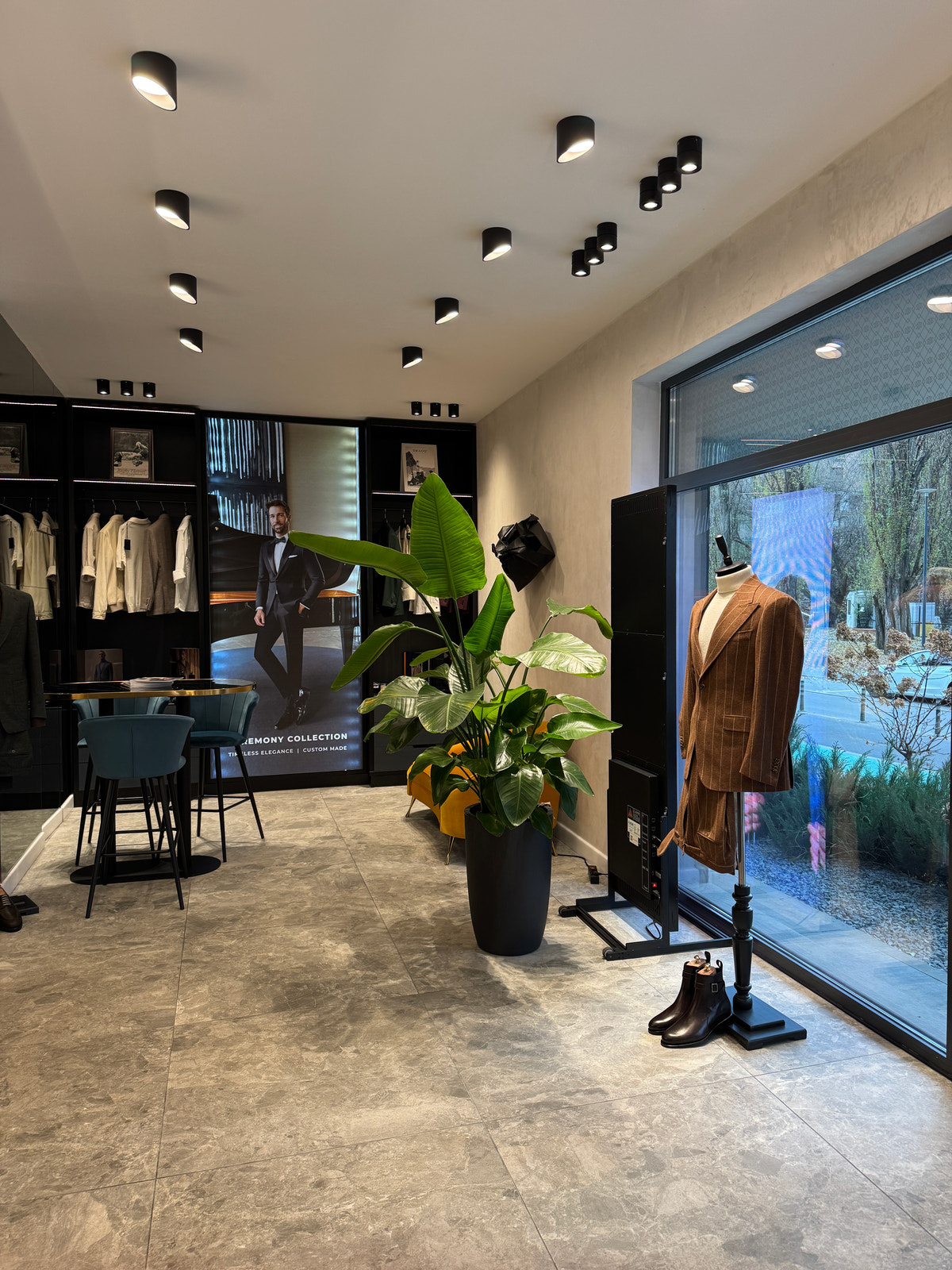 The light-filled window, with a brown outfit displayed beside plants.