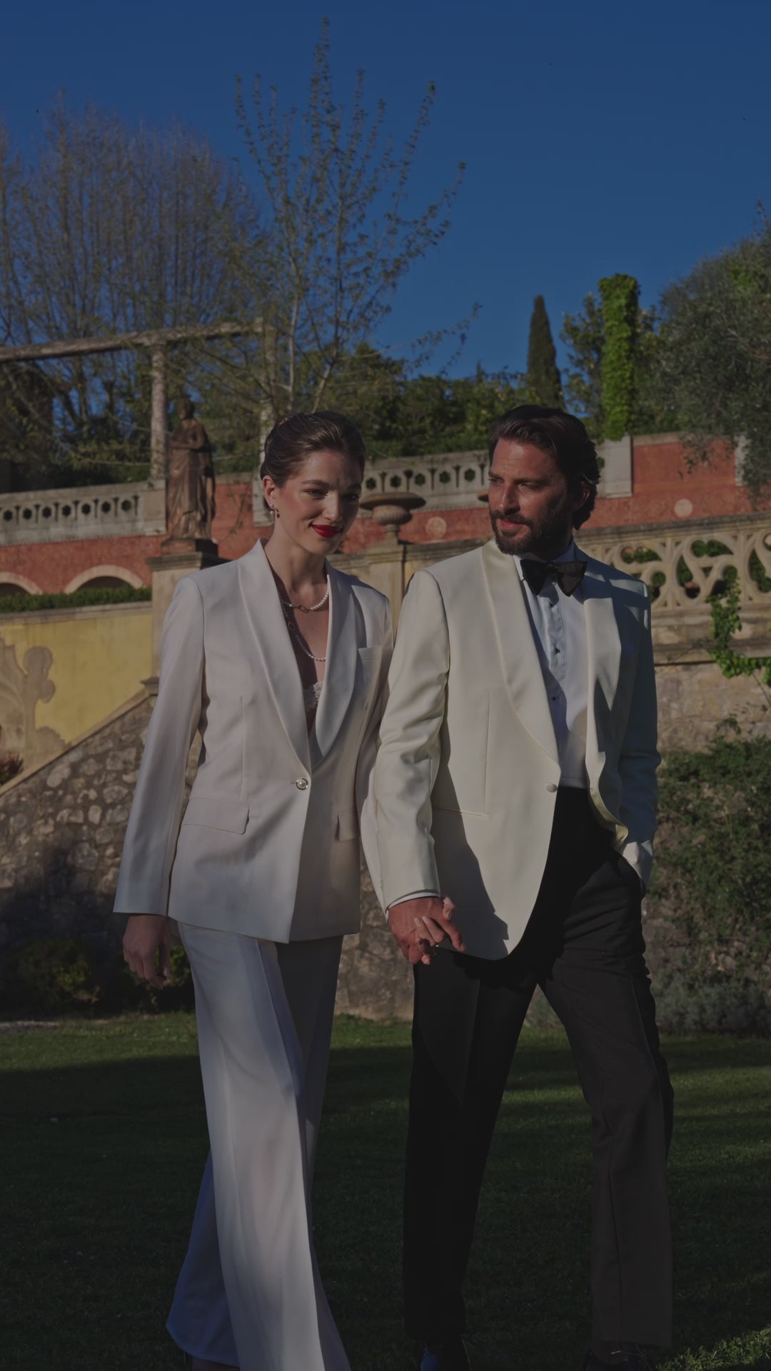 Consiglieri duo: an ivory women's suit and a men's tuxedo with a pale jacket