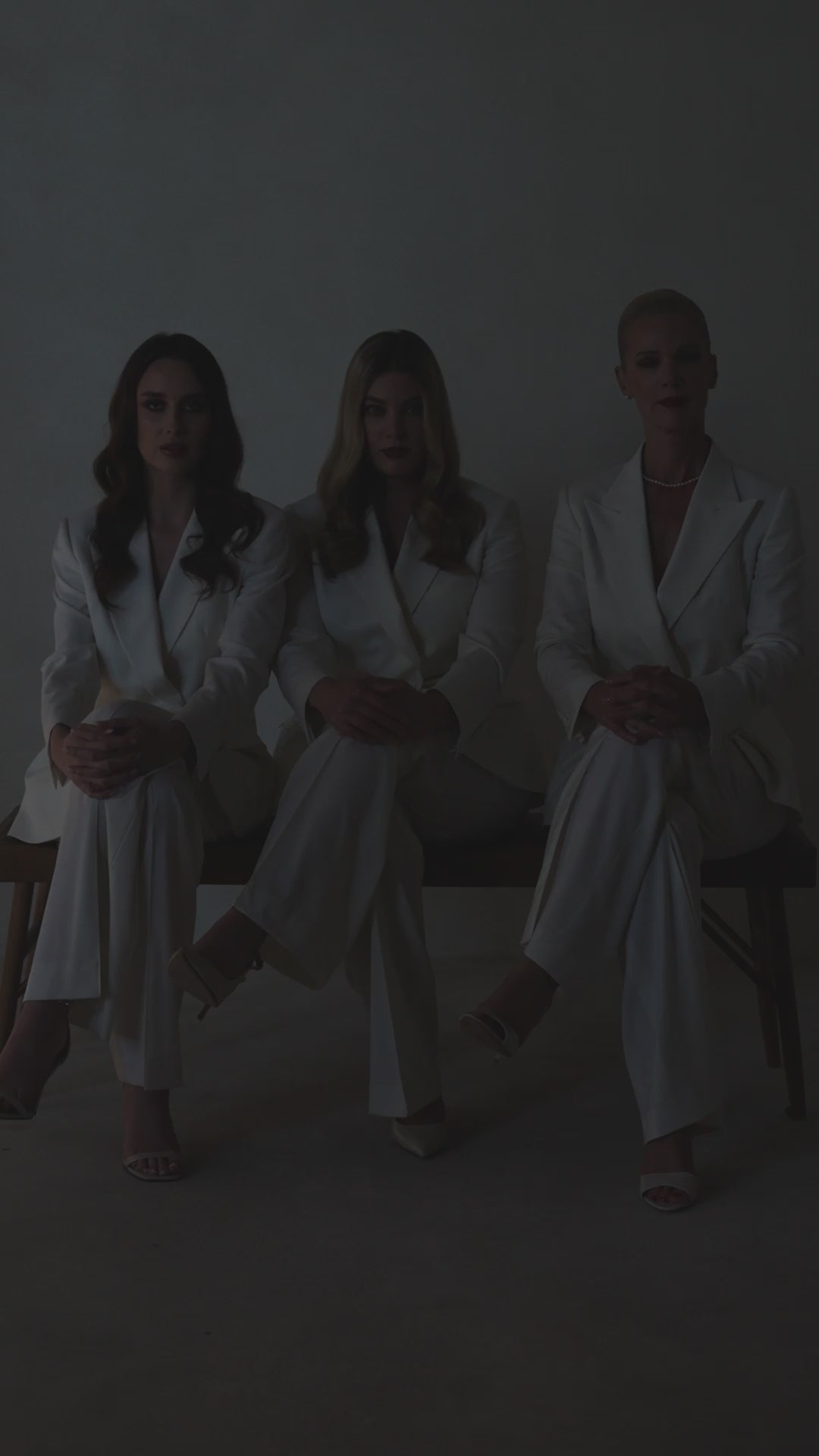 Three women seated together in ivory Consiglieri The Riviera Suit ensembles