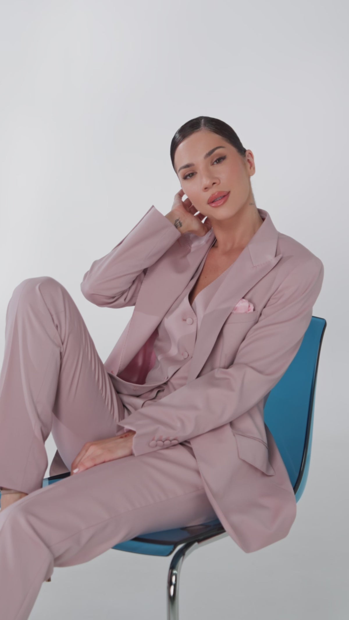Woman in a pale pink suit seated on a blue chair