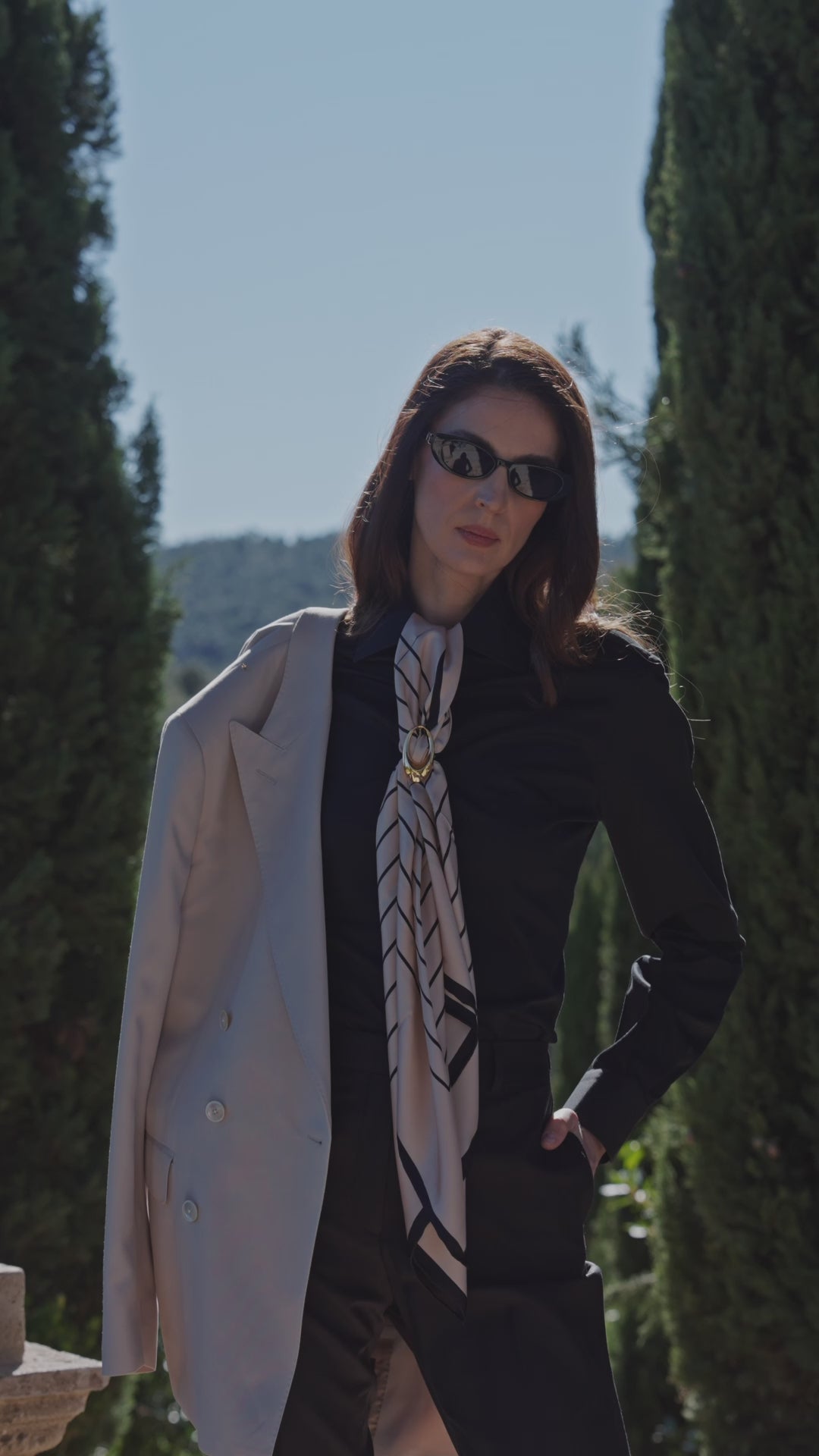 Consiglieri Éclipse Privée ensemble with a printed scarf and a pale coat over one shoulder